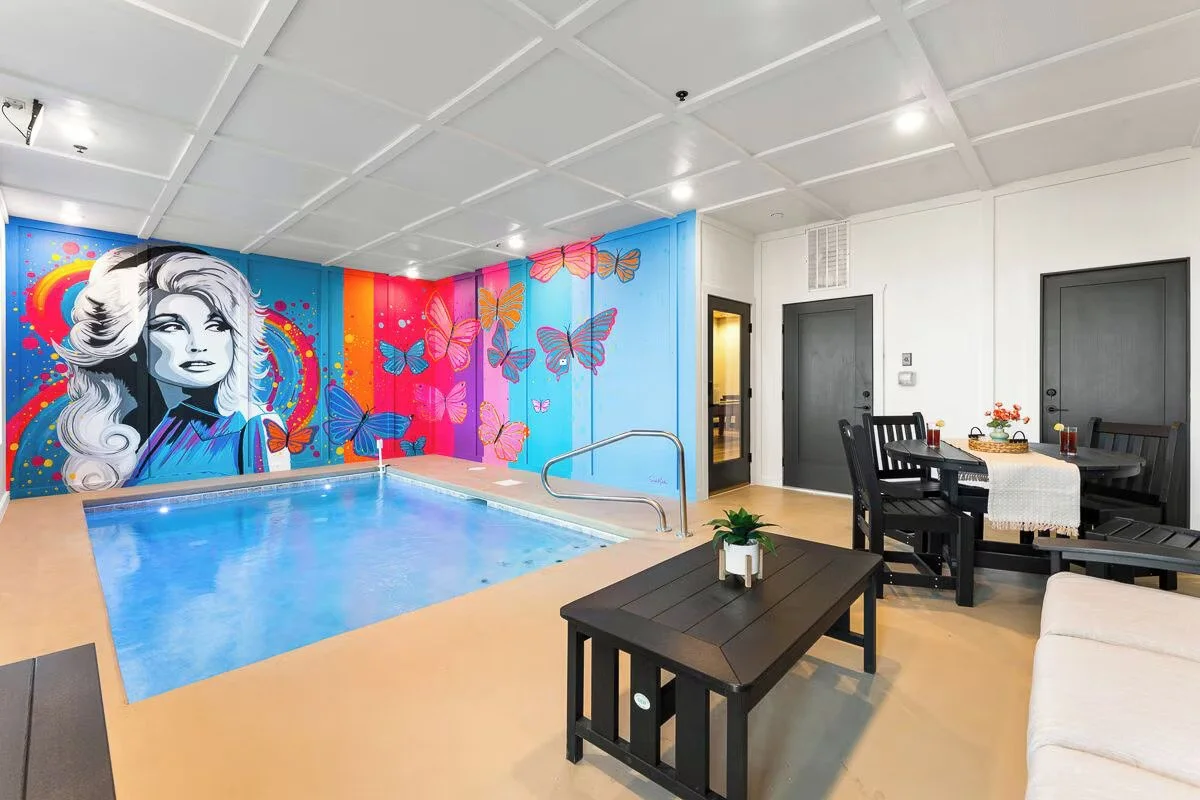 Vibrant neon-style Dolly Parton portrait mural with colorful butterflies in a Sevierville, Tennessee cabin.