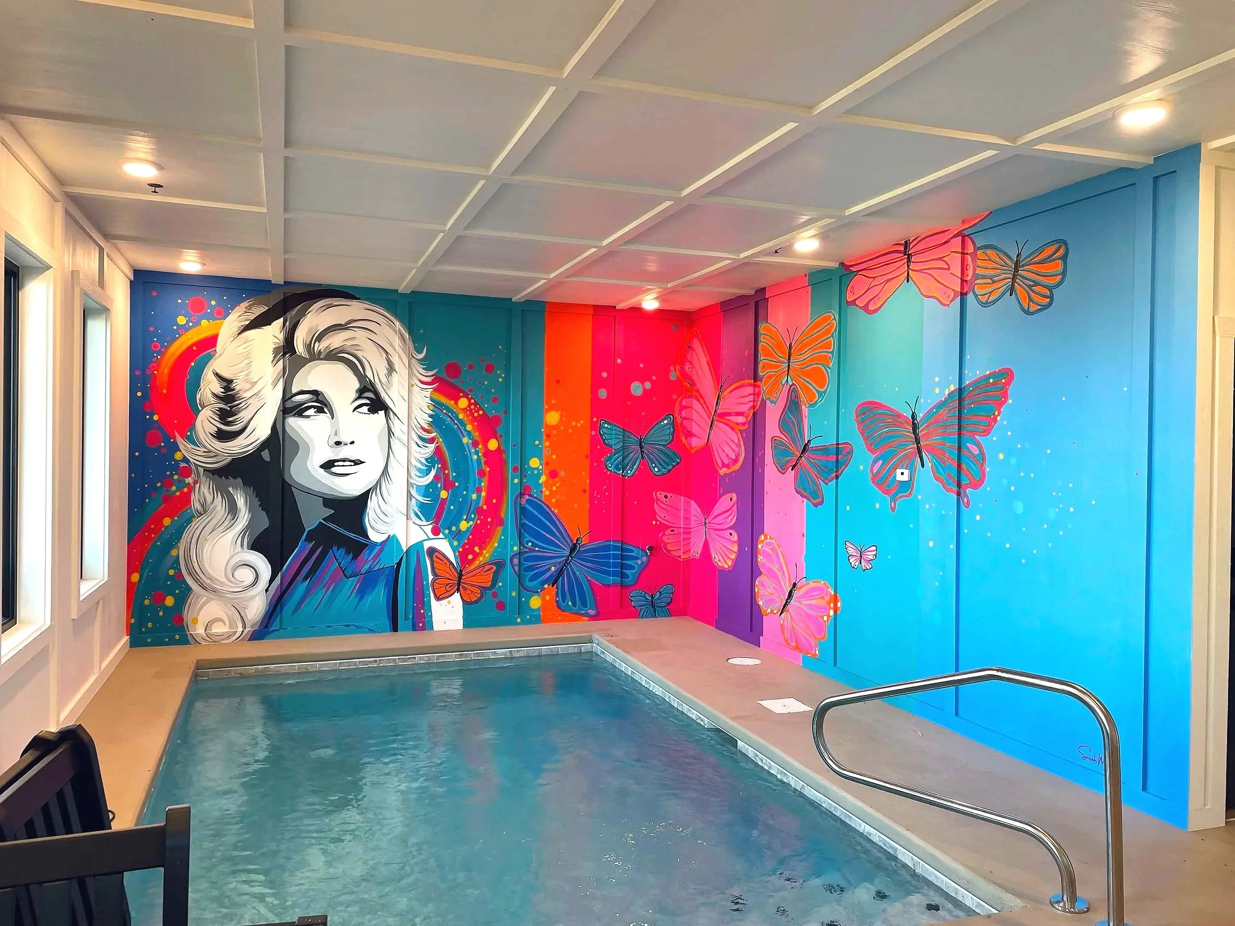 Vibrant neon-style Dolly Parton portrait mural with colorful butterflies in a Sevierville, Tennessee cabin.