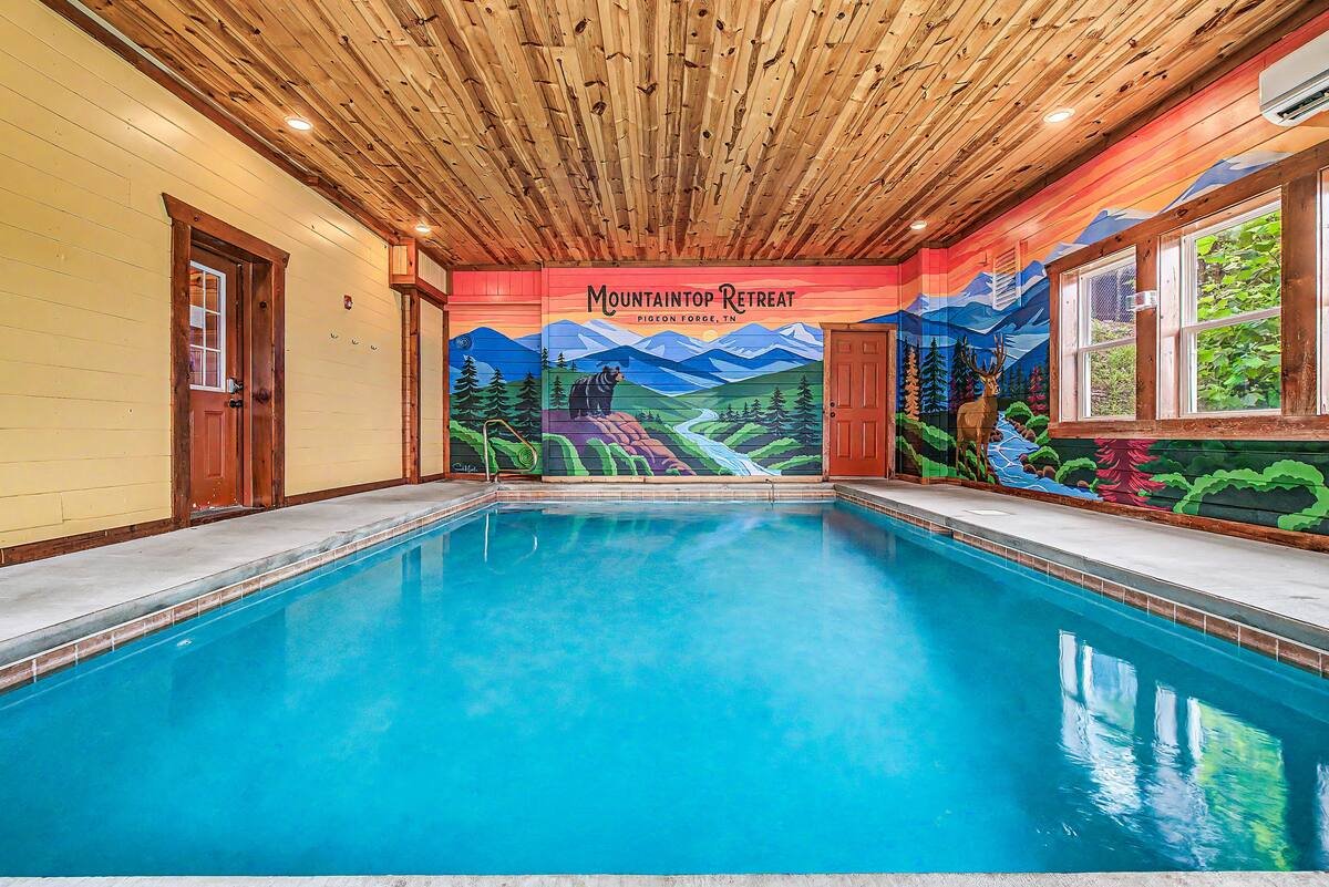 Custom indoor pool mural featuring the Smoky Mountains, elk, bear, and flowing stream in a cabin in Pigeon Forge, Tennessee.