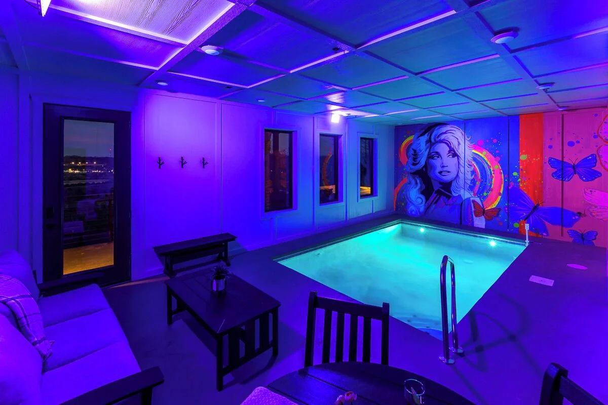 Vibrant neon-style Dolly Parton portrait mural with colorful butterflies in a Sevierville, Tennessee cabin.