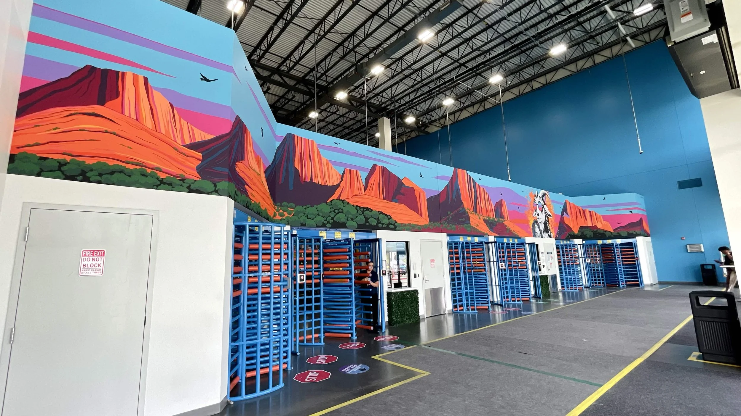 Custom Amazon warehouse entrance mural in Salt Lake City featuring a hiking goat with a backpack inspired by Zion National Park and Southern Utah scenery.