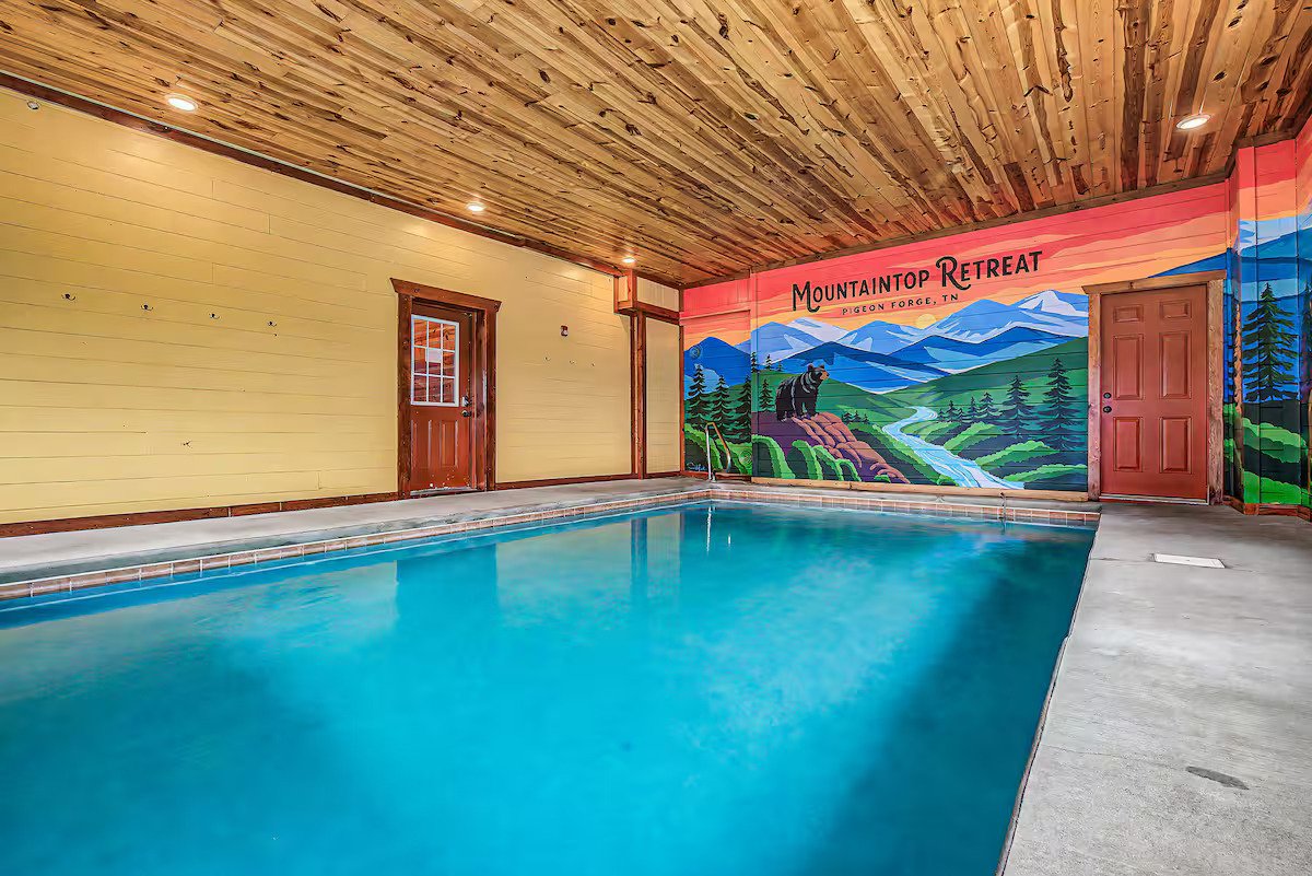 Custom indoor pool mural featuring the Smoky Mountains, elk, bear, and flowing stream in a cabin in Pigeon Forge, Tennessee.