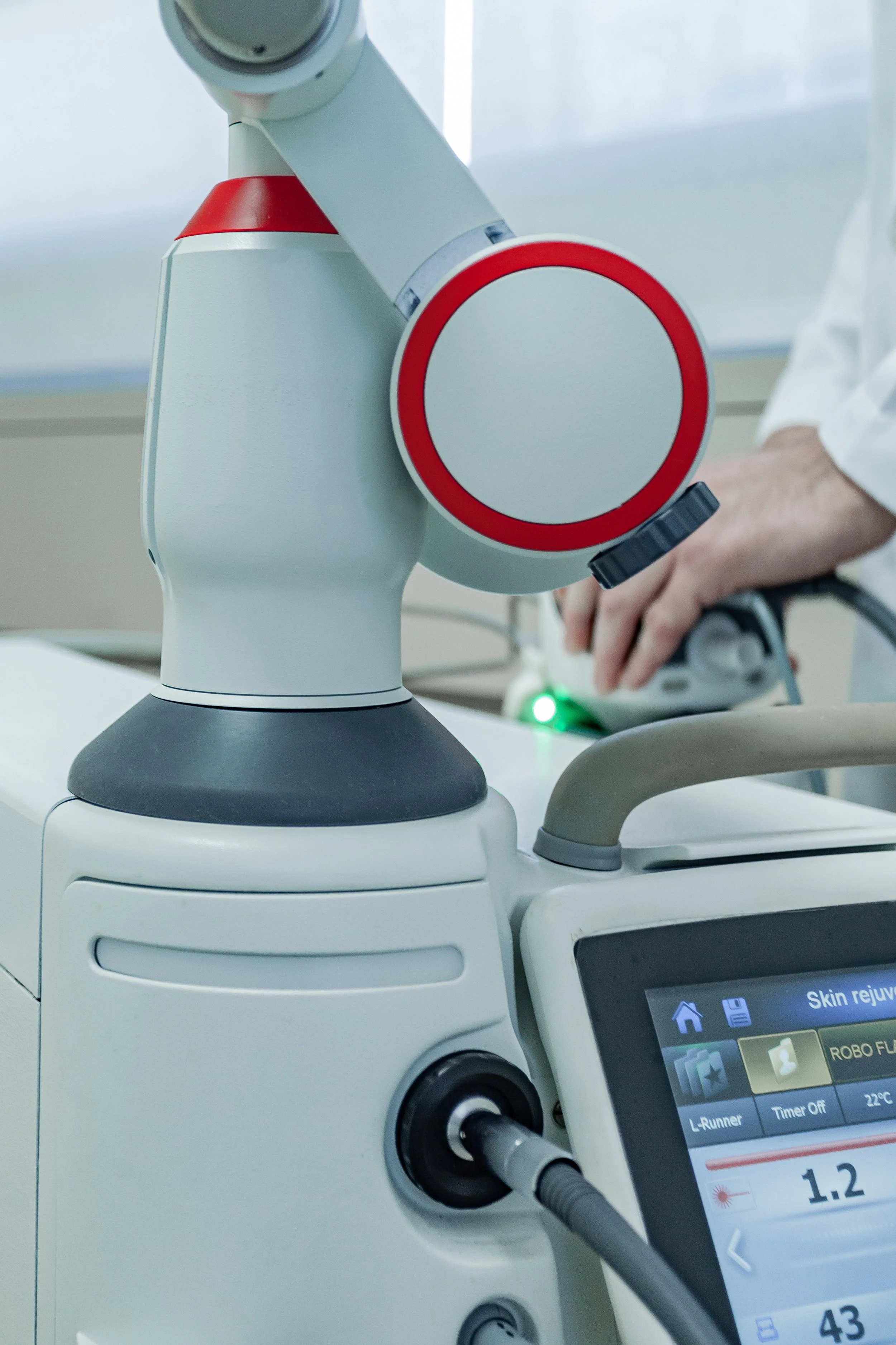 Medical equipment with a robotic arm and a digital control panel, used for skin rejuvenation treatments in a clinical setting.
