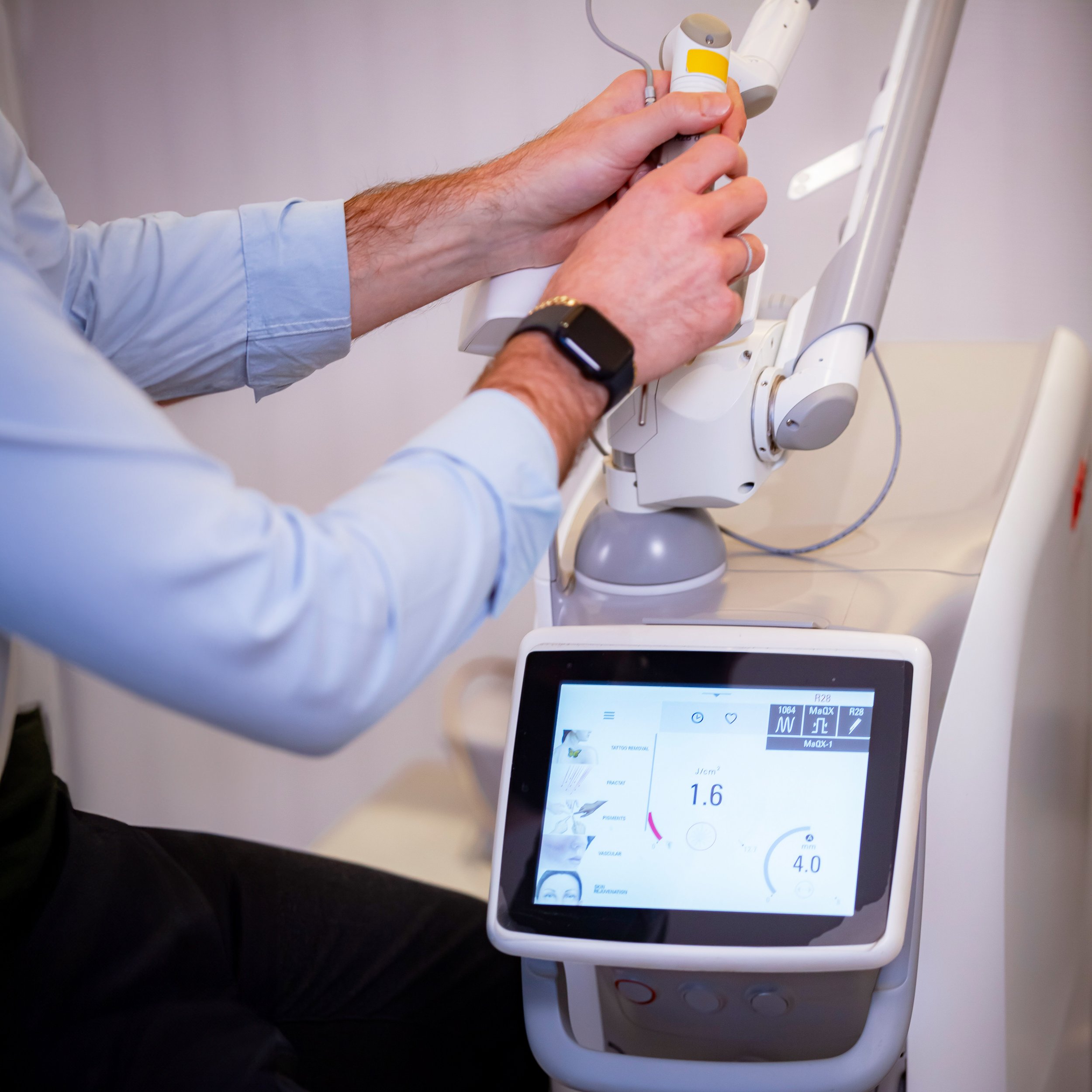 A medical professional using a robot-assisted device with a digital touchscreen interface displaying various settings.