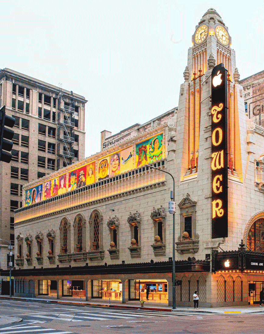 Exterior of the Tower Theatre in Los Angeles, with marquee signage, colorful artwork, and a clock tower.