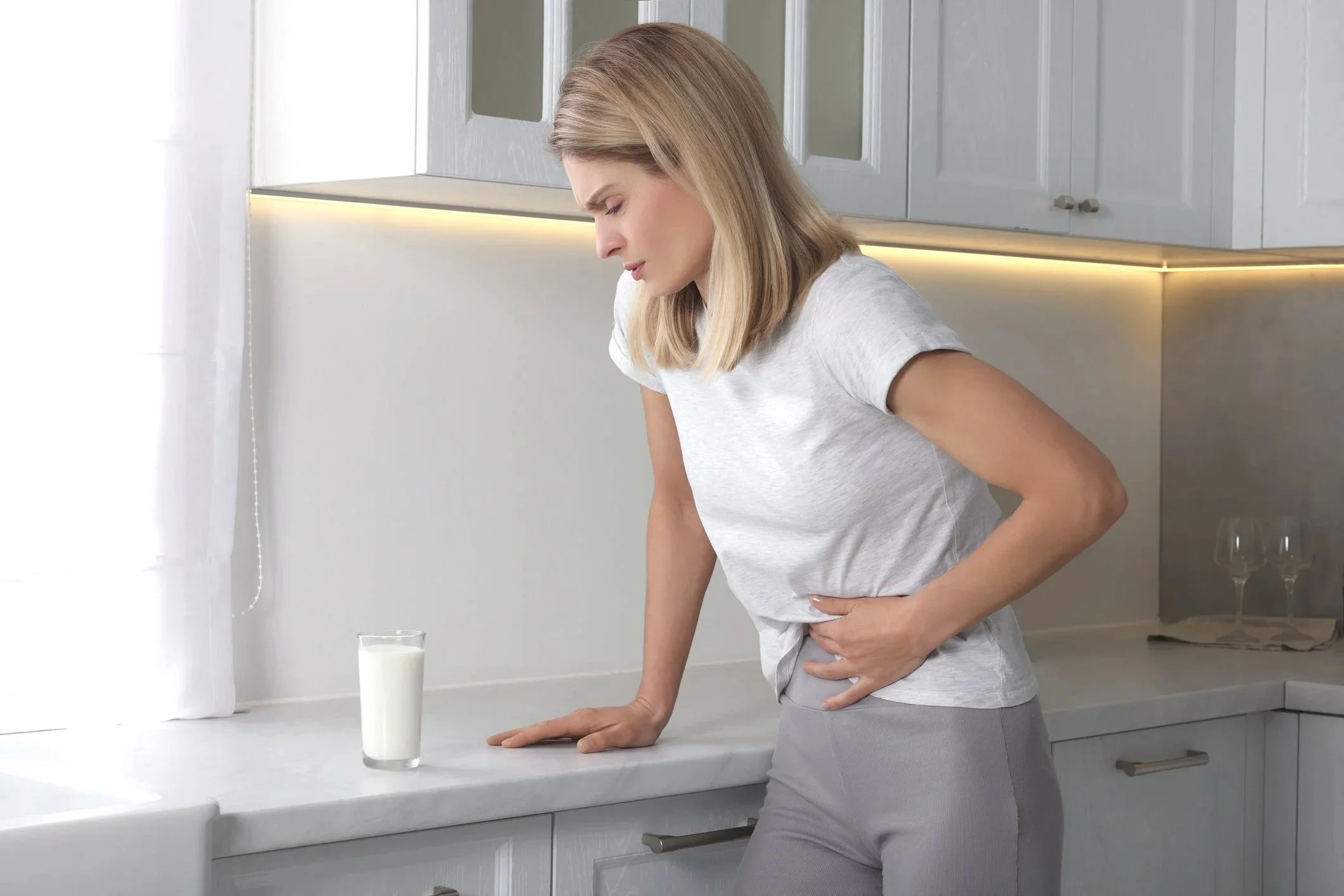 Person holding bread with hand on stomach, loaf on table.