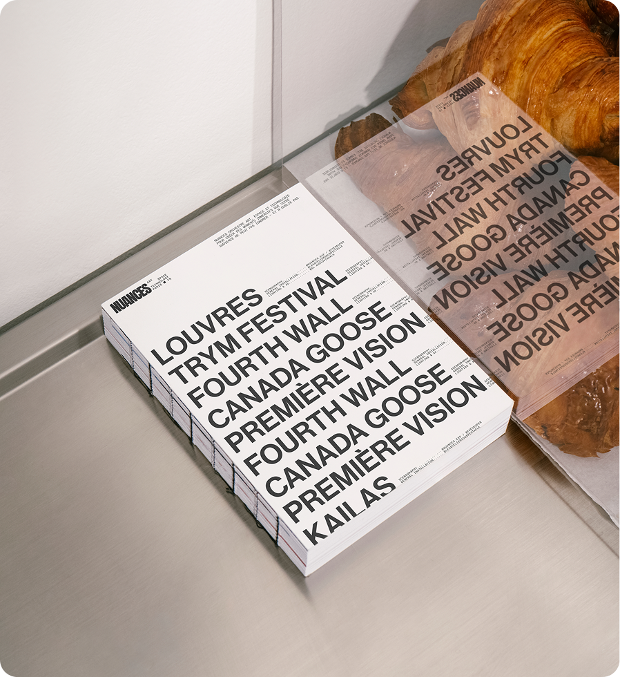 Affiche blanche avec texte noir listant des noms d'expositions et d'événements artistiques, comme Louvre, Trym Festival, Fourth Wall, Canada Goose, Première Vision, Kai As, et d'autres. L'affiche est posée sur une surface métallique.