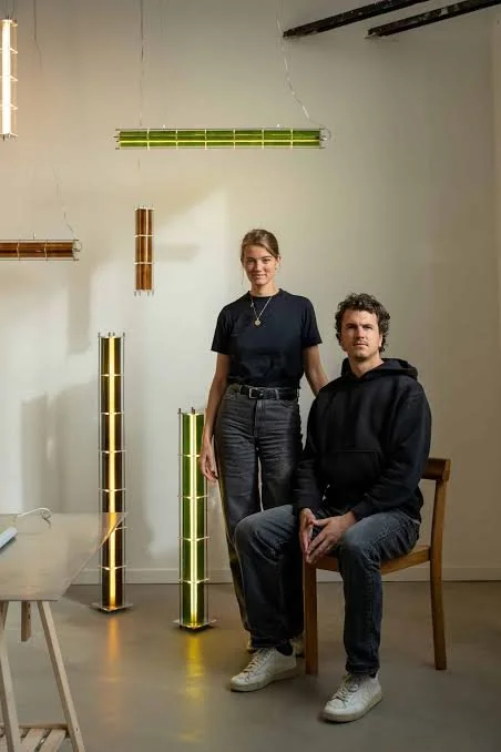 Deux personnes posent dans un espace avec des tubes lumineux suspendus et posés, ambiance artistique.