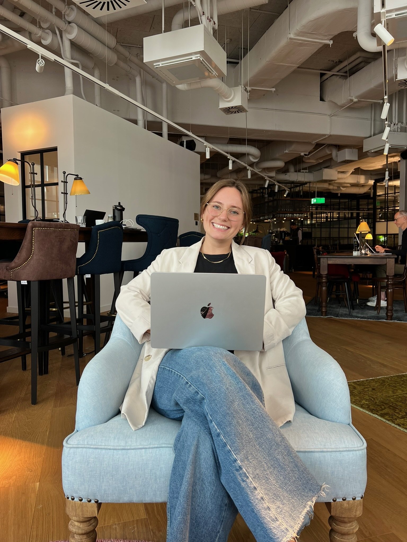 Founder Vivi sitzt auf einem Sessel mit einem Laptop auf dem Schoß, lächelt freundlich in die Kamera