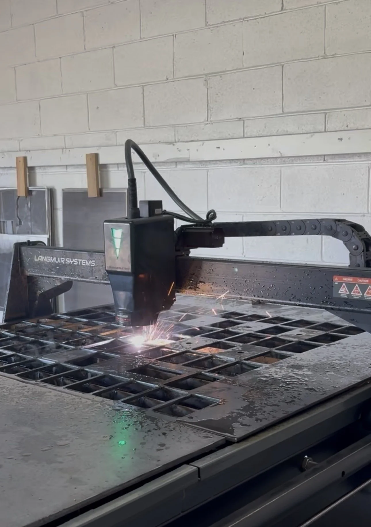 A laser cutting machine performing a precise cut on a metal grid on a table in an industrial workshop.