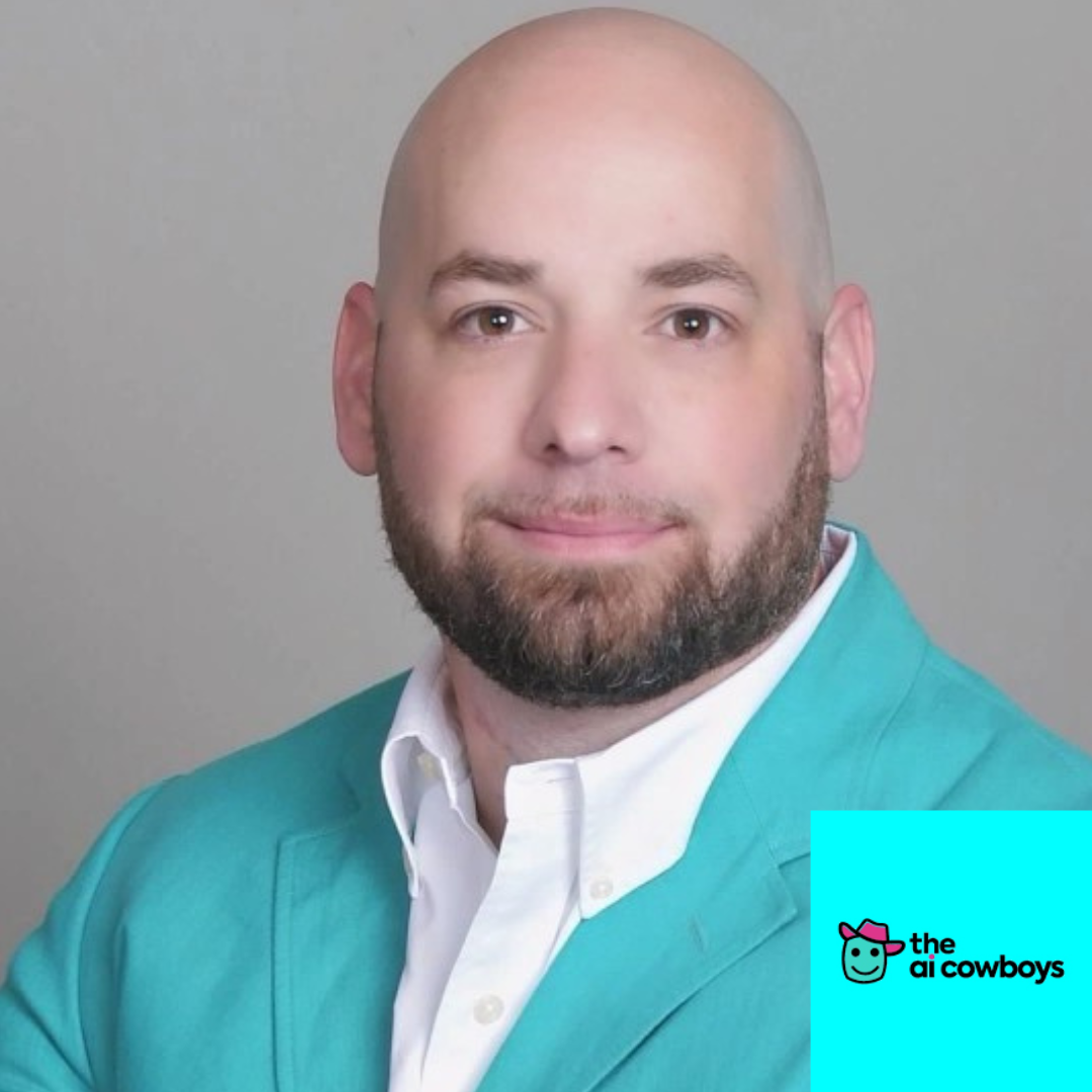 A man with a beard and bald head, wearing a turquoise blazer and white shirt, posing for a professional headshot against a gray background.