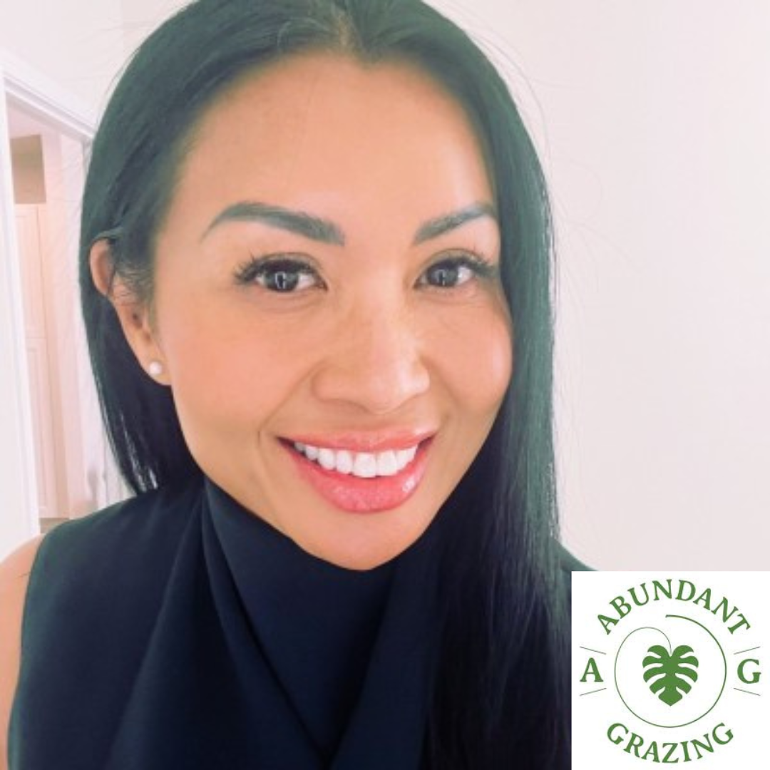 A smiling woman with long black hair and pearl earrings, wearing a black sleeveless top, in front of a white background with a logo that says 'Abundanti Grazing' and features a leaf design.
