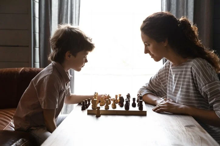 Fulham nanny engaged in a game of chess with child to develop the child critical thinking and problem solving.