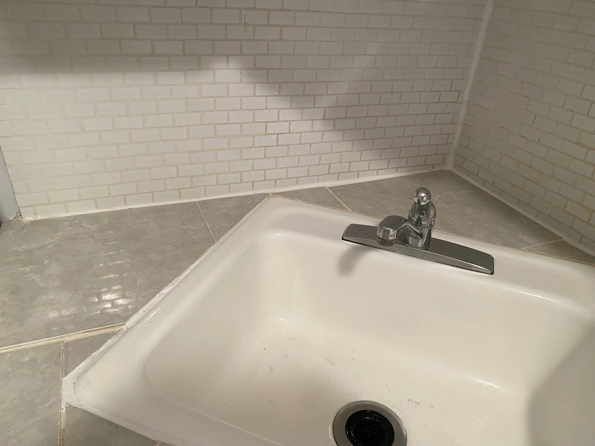 Caulking and tile work cleanup around bathtub in a classic Upper East Side (UES) bathroom.