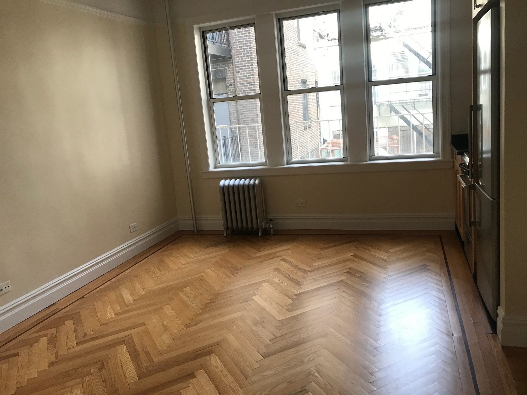 Post-paint cleanup and floor polish in this sun-filled West Village living room. Restored the shine without over-sanding.