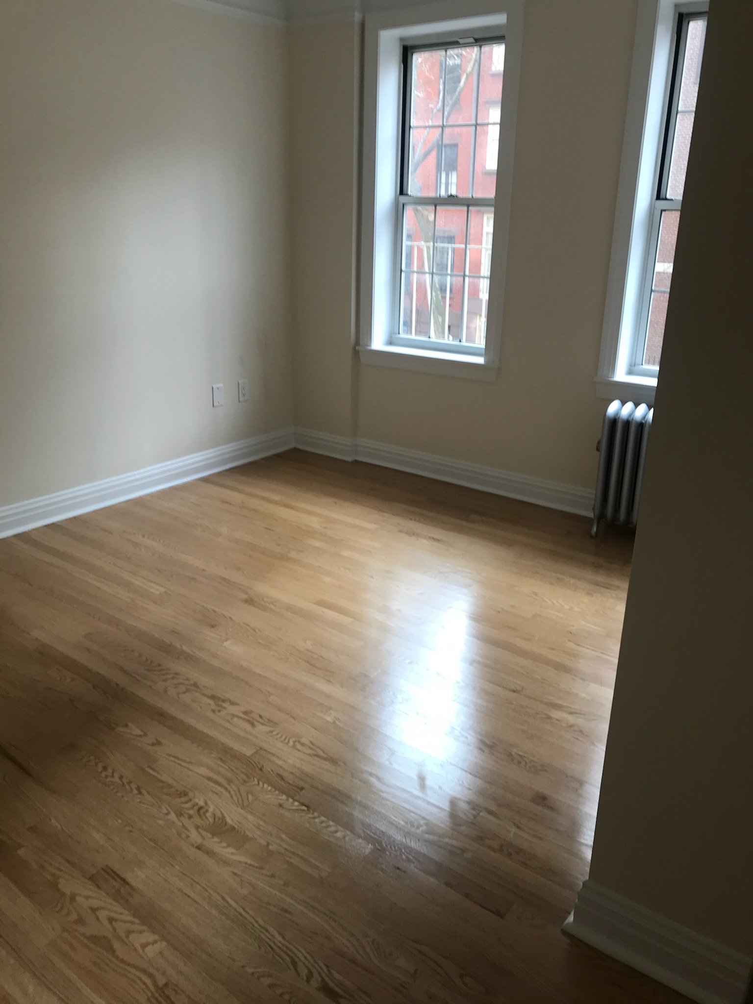 Floor refinished and baseboard touchup in this corner West Village bedroom. Natural light brought to life with a clean finish.