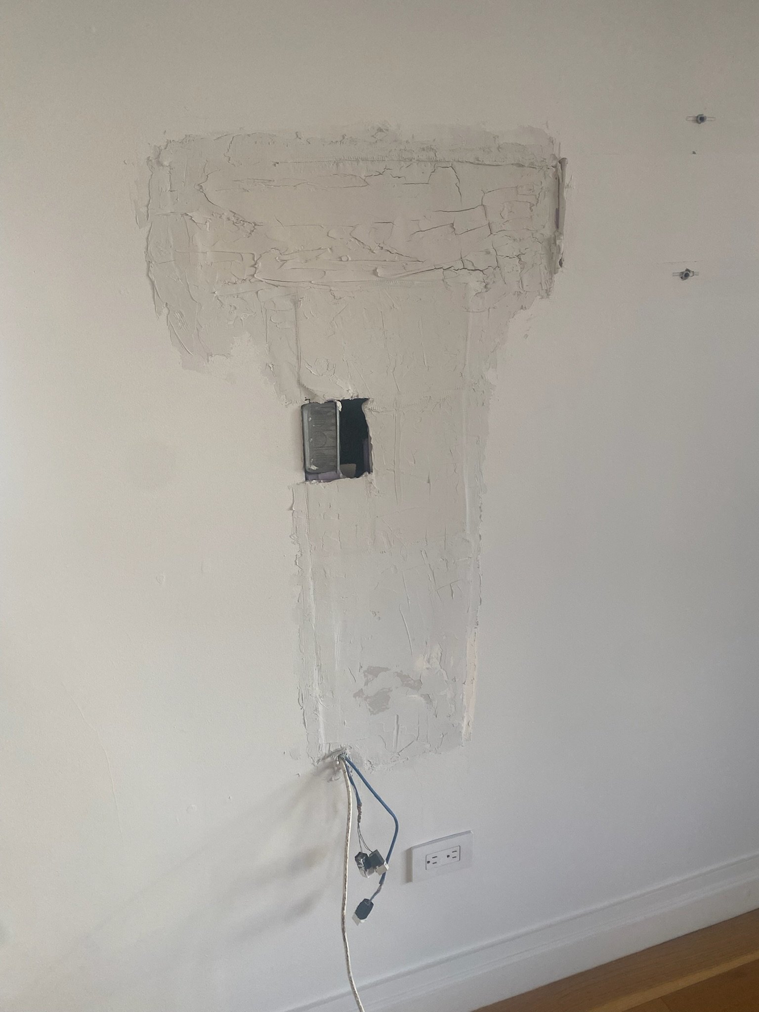 Drywall repair and cable re-routing for a media setup in a bright Upper East Side (UES) apartment. Wall ready for paint and clean mounting.