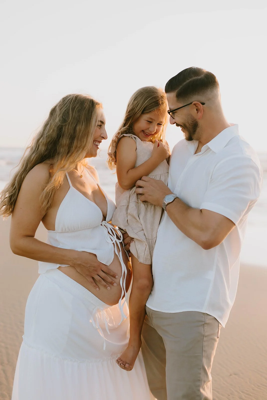 Carefree family laughing and playing during maternity session at Huntington Beach — Best candid family photographers in Huntington Beach — Captured by Tesla Rae Photo