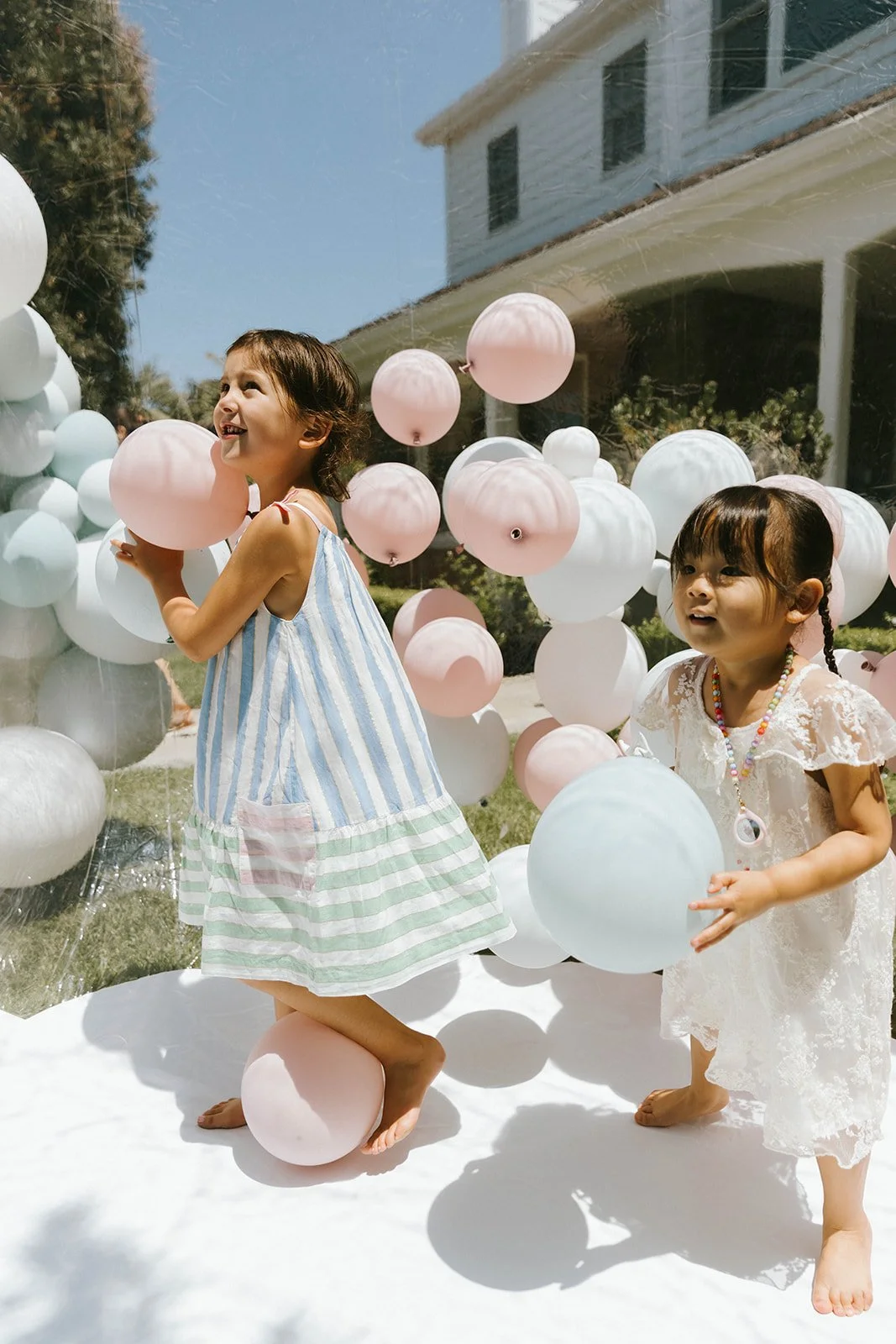 Children playing with pastel balloons during a stylish backyard birthday celebration in Orange County, California captured with candid lifestyle event photography and joyful summer party moments.