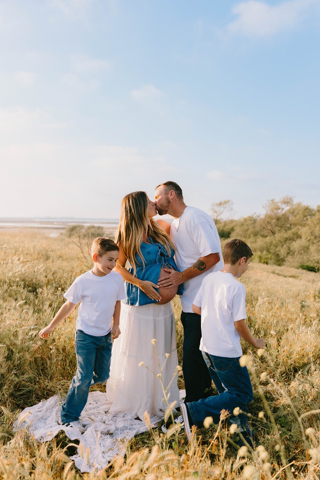 Candid family portrait at sunset in green, golden field in Costa Mesa — Best maternity photographers in Orange County — Tesla Rae Photo