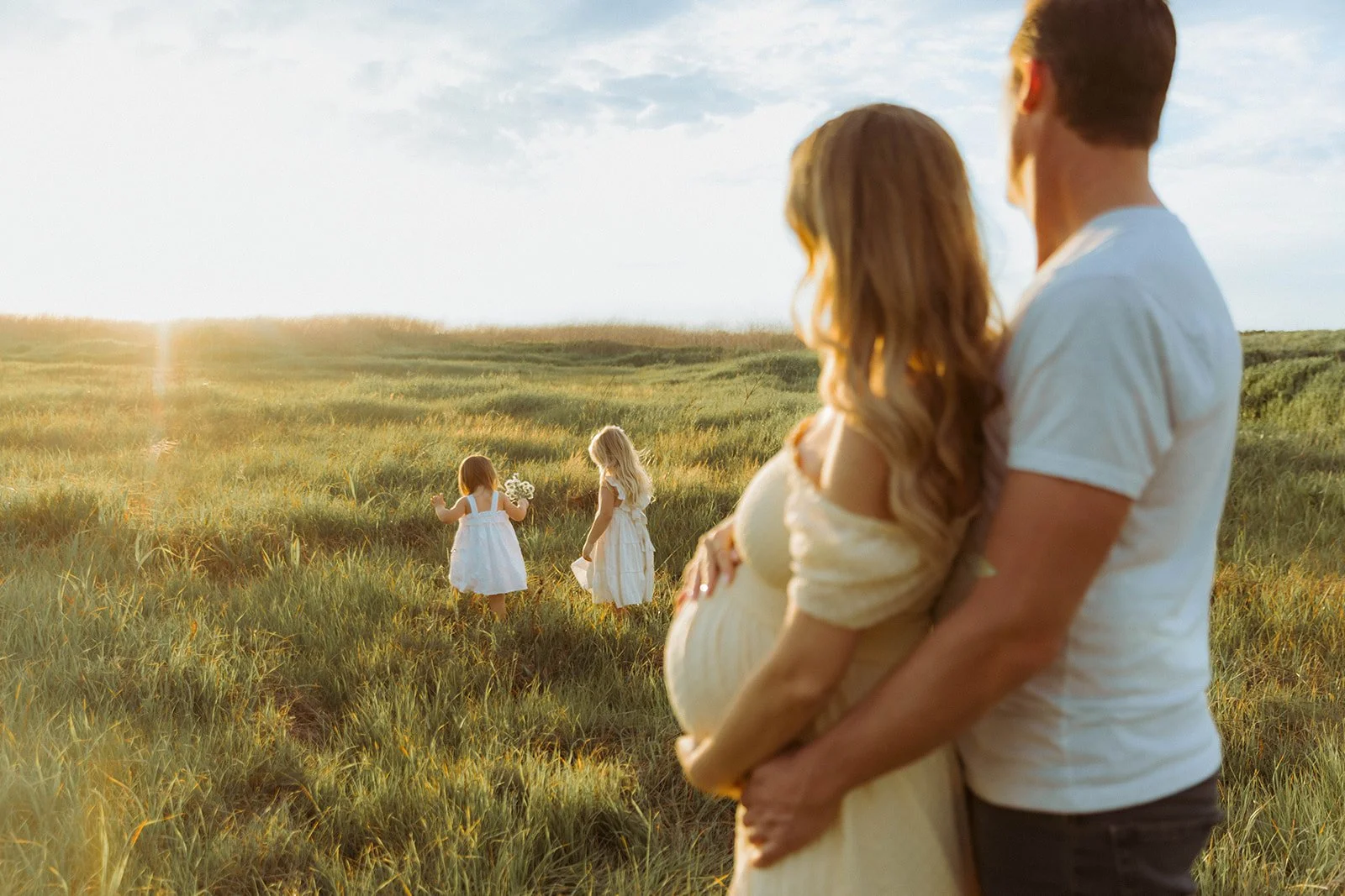Candid family portrait at sunset in green, golden field in Costa Mesa — Best maternity photographers in Orange County — Tesla Rae Photo