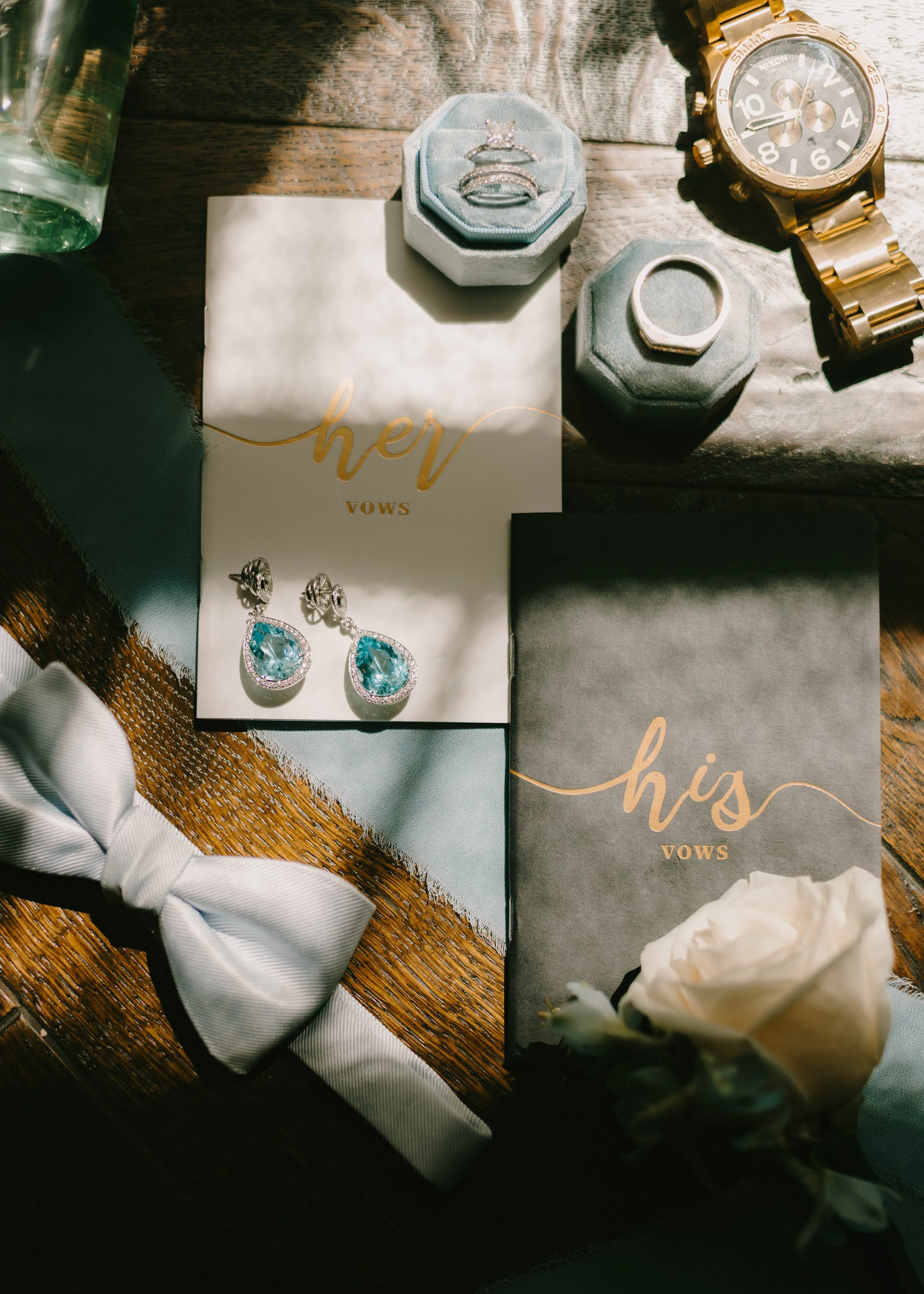 A curated collection of wedding details including invitation suites, rings, perfume, heirloom touches, and bridal accessories styled together in soft natural light. Elegant editorial wedding flat lay photography with timeless, romantic styling.
