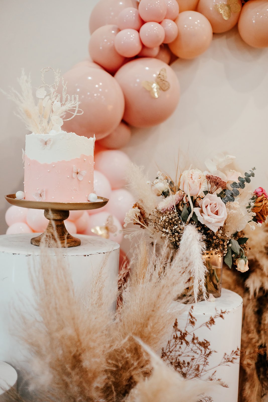 
Elegant floral centerpiece with ballon arch in the background and gorgeous cake at high-end baby shower at Fullerton Arboretum