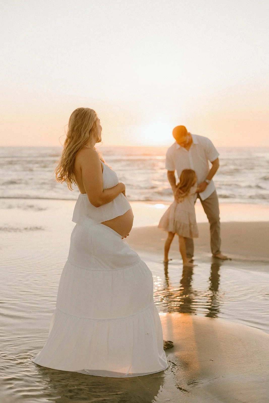 Carefree family laughing and playing during maternity session at Huntington Beach — Best candid family photographers in Huntington Beach — Captured by Tesla Rae Photo
