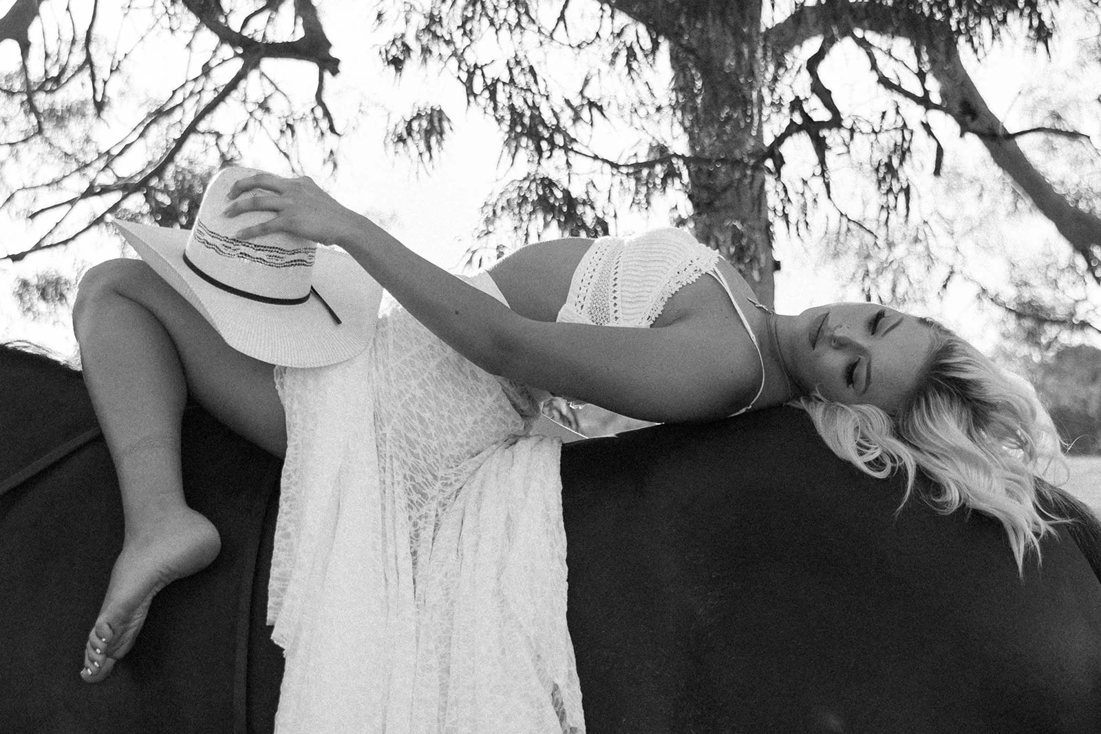 Black and white photo of girl holding cowboy hat while laying backwards on her horse at the horse stables in Huntington Beach— Best brand photographers in Huntington Beach — Captured by Tesla Rae Photo