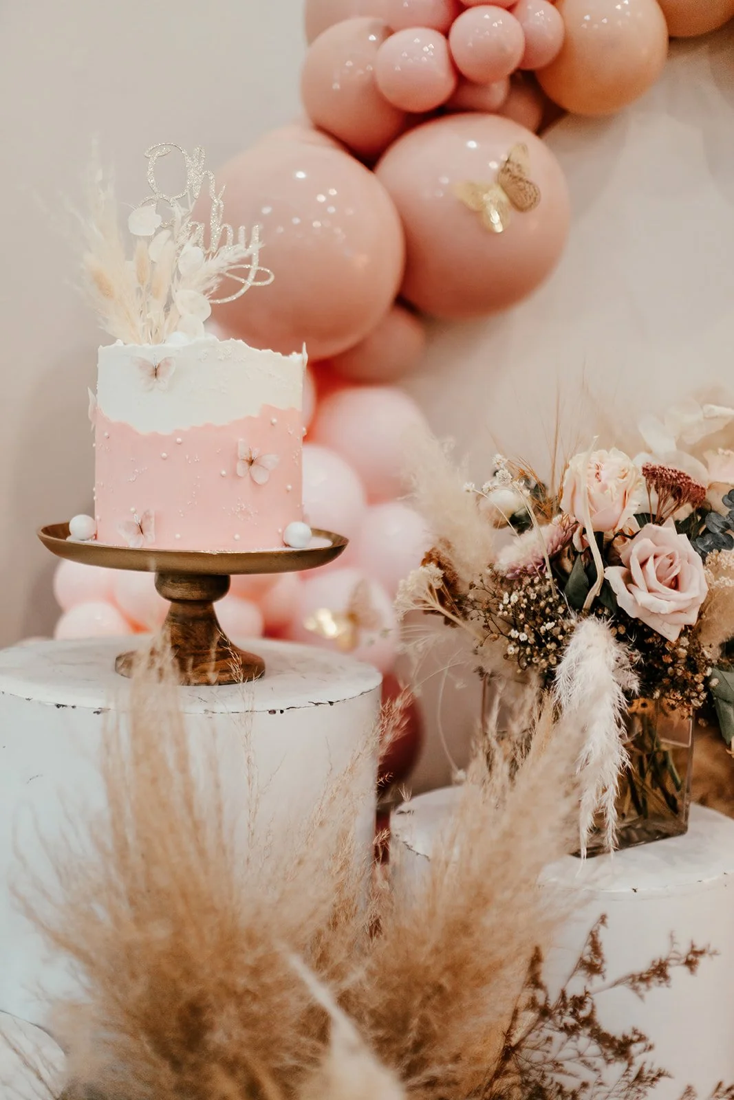 

Elegant floral centerpiece with ballon arch in the background and gorgeous cake at high-end baby shower at Fullerton Arboretum