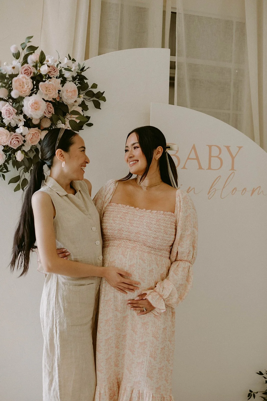 Candid shot of pregnant women posing with friend in front of photo backdrop at baby shower at Still Interior event space in Costa Mesa — Orange County event photographer Tesla Rae Photo