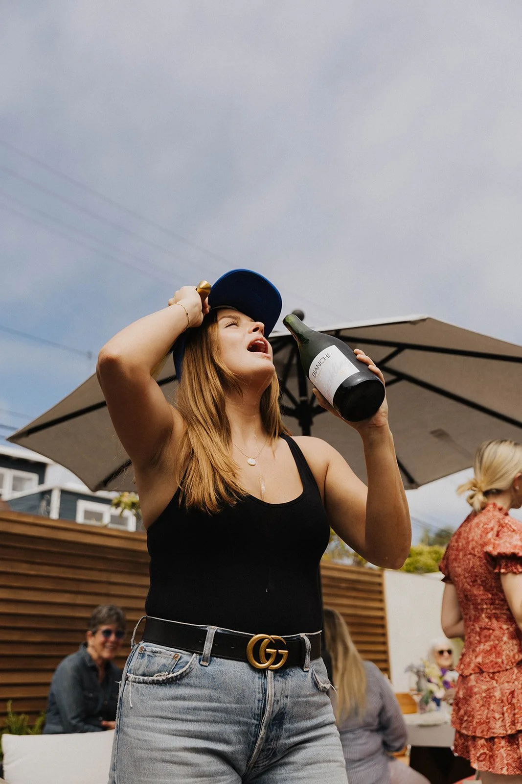 Women drinking champagne out of the bottle with head tilted back during intimate ladies' networking event at Bianchi Laguna Beach— Luxury event photographer Tesla Rae Photo based in Southern California