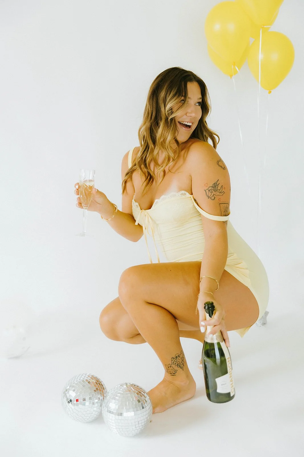 Celebratory, lifestyle birthday portraits of girl holding champagne glass next to champagne bottle and disco ball in Huntington Beach, natural light studio — Best brand photographers in Huntington Beach — Captured by Tesla Rae Photo