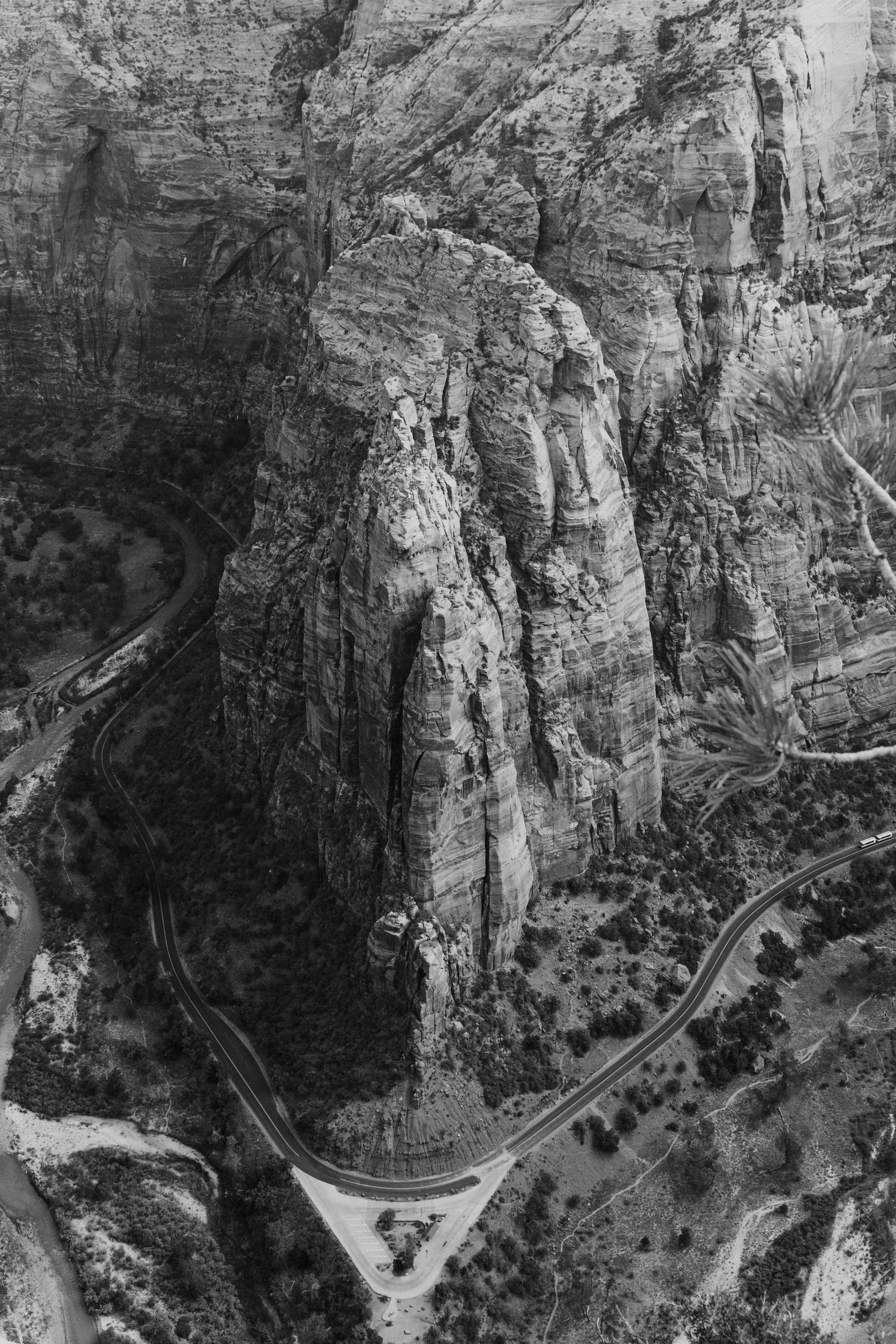 An aerial black-and-white photograph of rugged, tall rock formations with a winding road at the base.