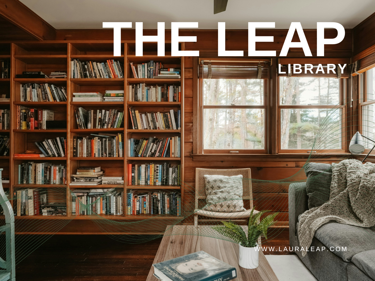 The Leap Library — a warm, wood-paneled reading room with floor-to-ceiling bookshelves, a tree-lined window, and a cozy couch with a knit throw.
