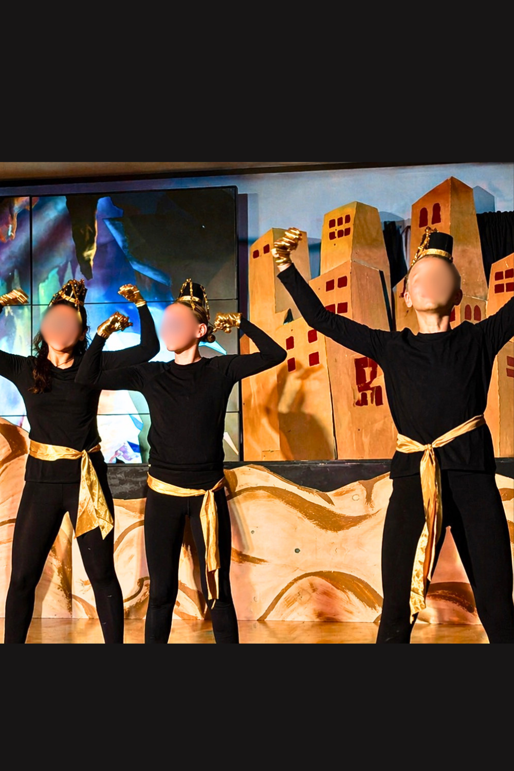 Cave of Wonders ensemble in Aladdin Jr wearing black costumes with gold belts and headpieces during a school musical performance scene.