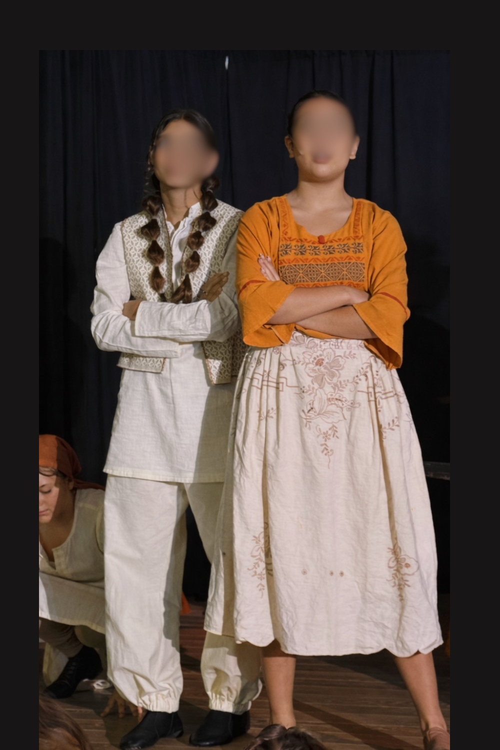 Agrabah shopkeepers in Aladdin Jr wearing white and neutral-toned costumes, standing on stage during a school musical performance scene.