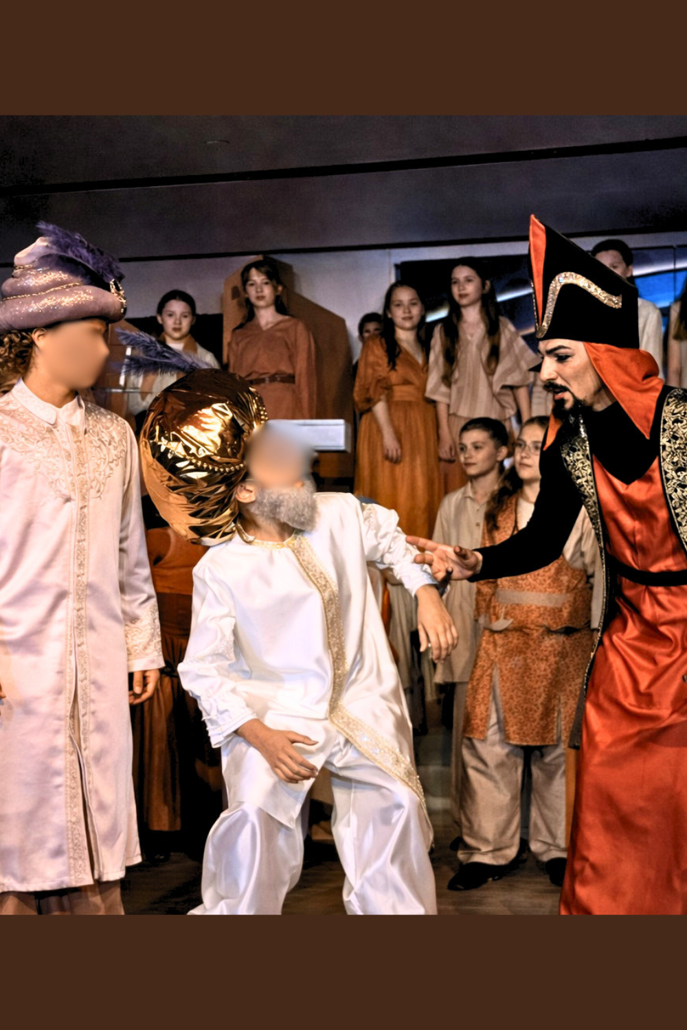Jafar confronting the Sultan with Prince Ali nearby in Aladdin Jr, wearing black and red robe, white Sultan costume, and cream princely outfit during a school musical scene.