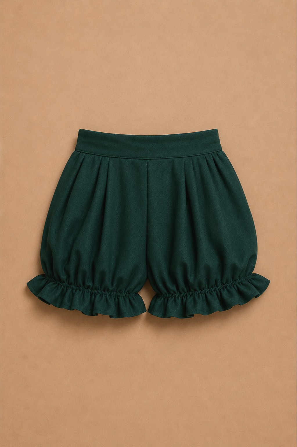 Dark green puffed shorts with ruffled hems on a beige background.