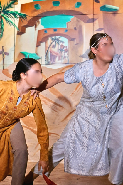 Storytellers in the opening scene of Aladdin Jr wearing textured neutral and gold-toned costumes, performing on stage during a school musical.