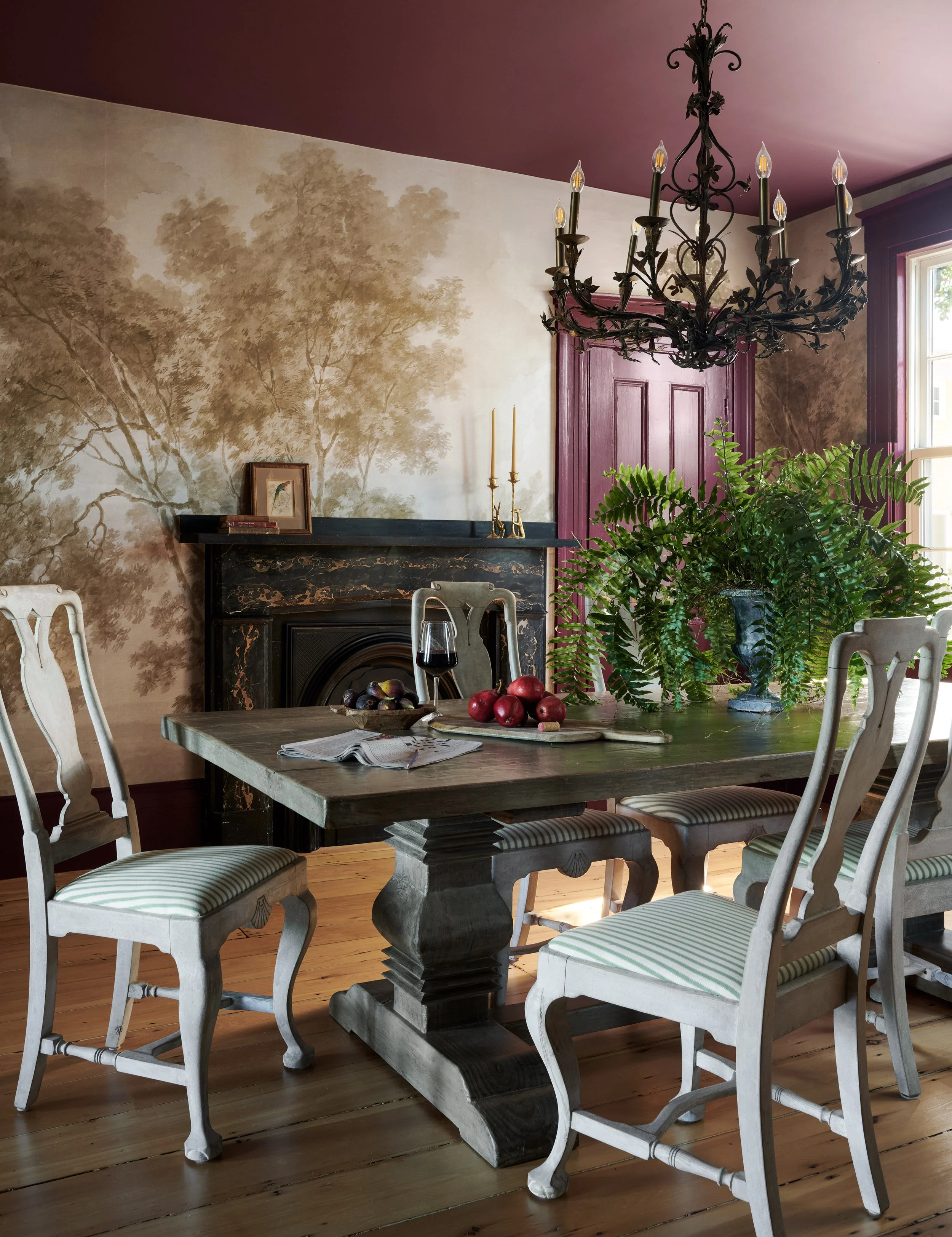 Dining room with a scenic tree mural, plum ceiling and iron chandelier at Summer Street, Newburyport, designed by Ivory & Bone Interiors