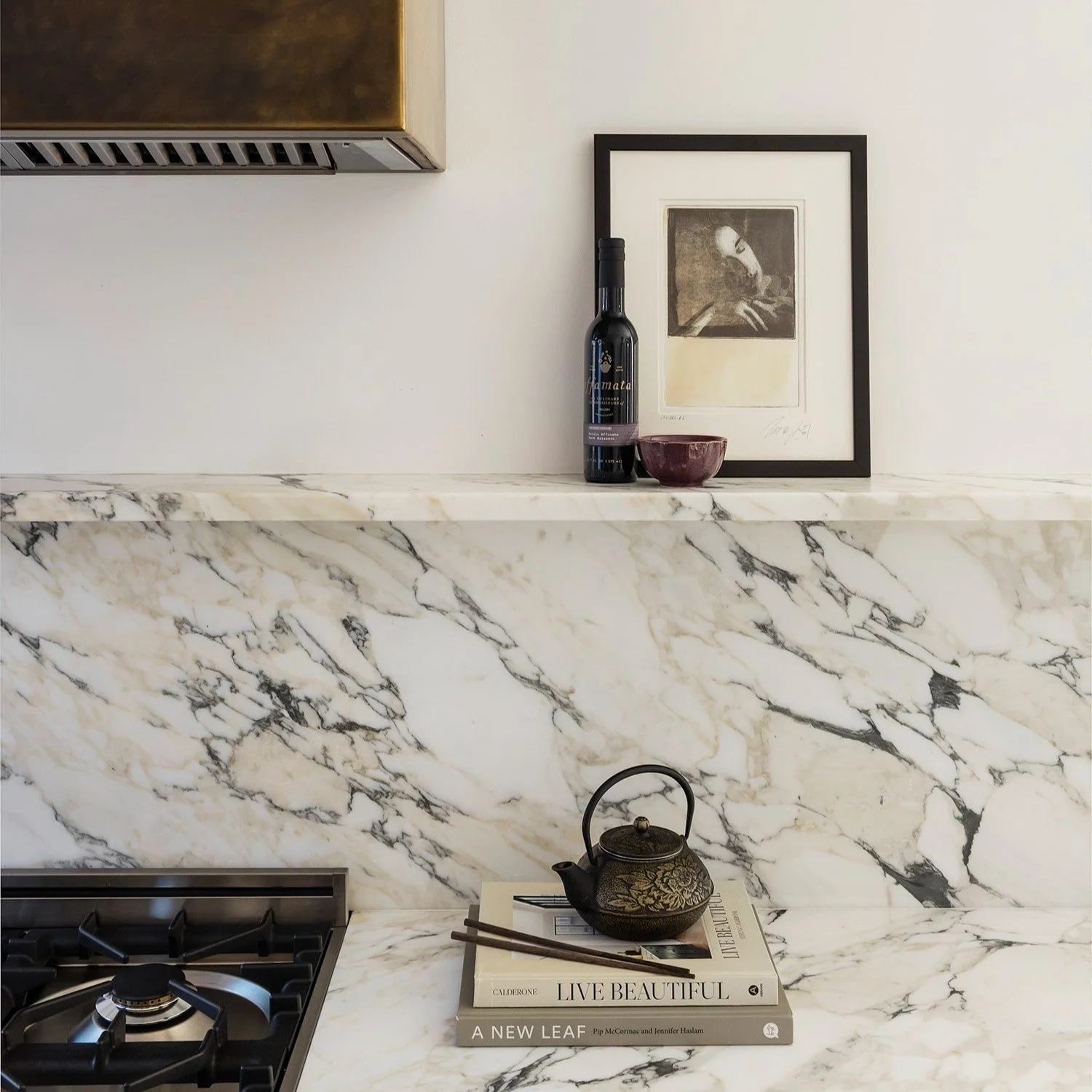 Marble kitchen with veined marble backsplash and brass range hood in a South End Boston residence on Clarendon Street