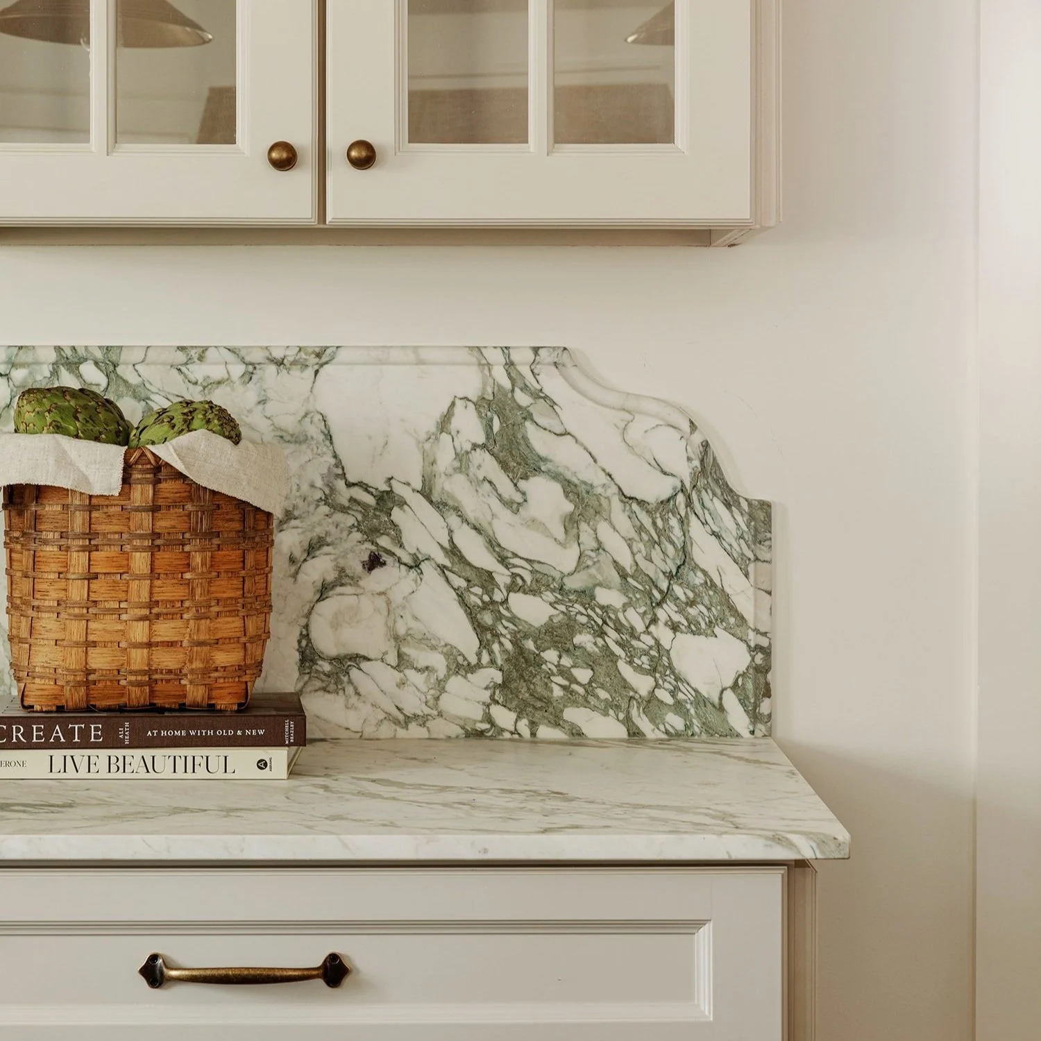 Green-veined marble countertop and scalloped backsplash with a woven basket at Salem Street, Newburyport, MA, designed by Ivory & Bone Interiors