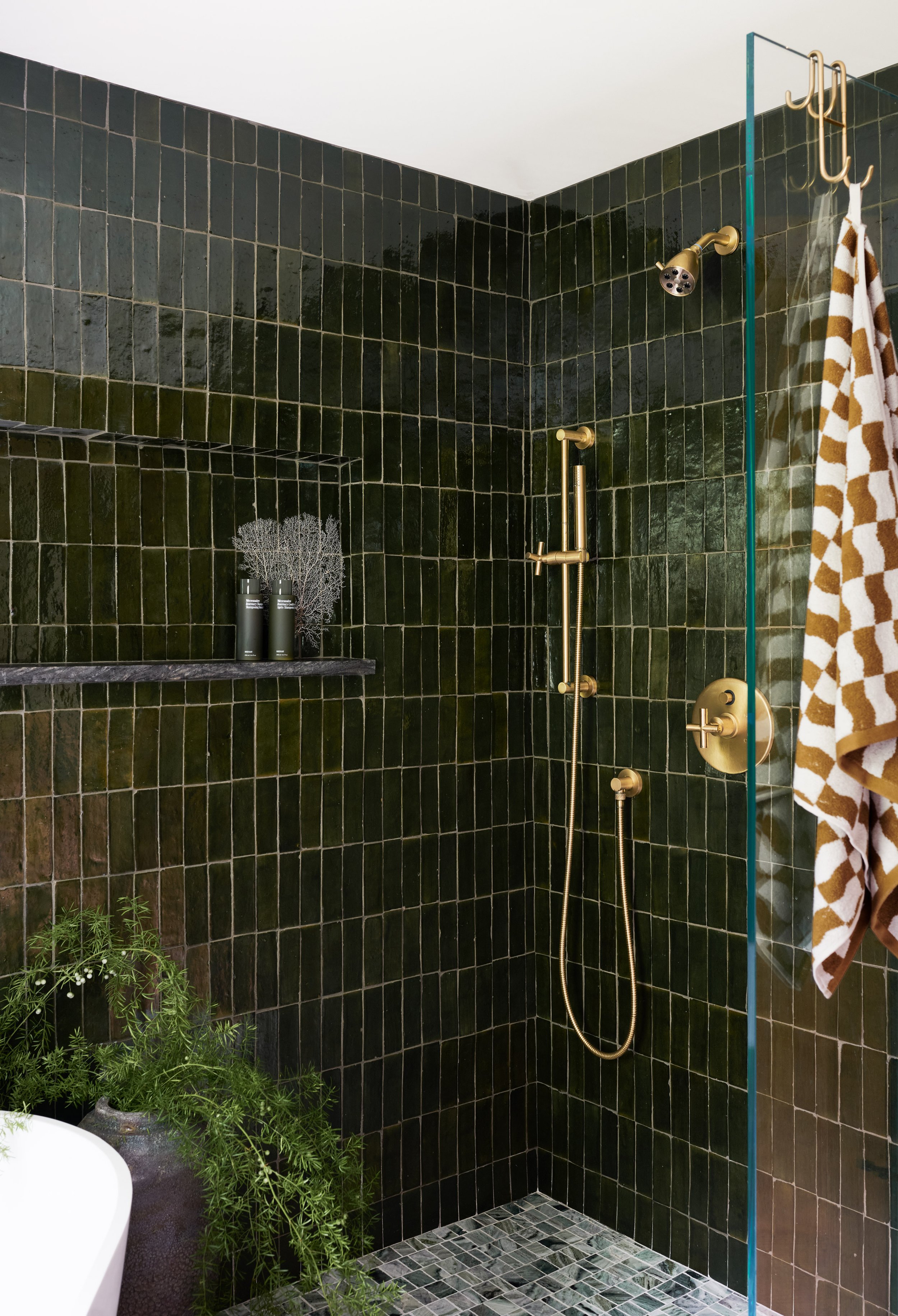 Glass-enclosed shower with deep green glazed tile, exposed brass shower fittings and marble mosaic floor by Ivory & Bone Interiors, Groveland, MA