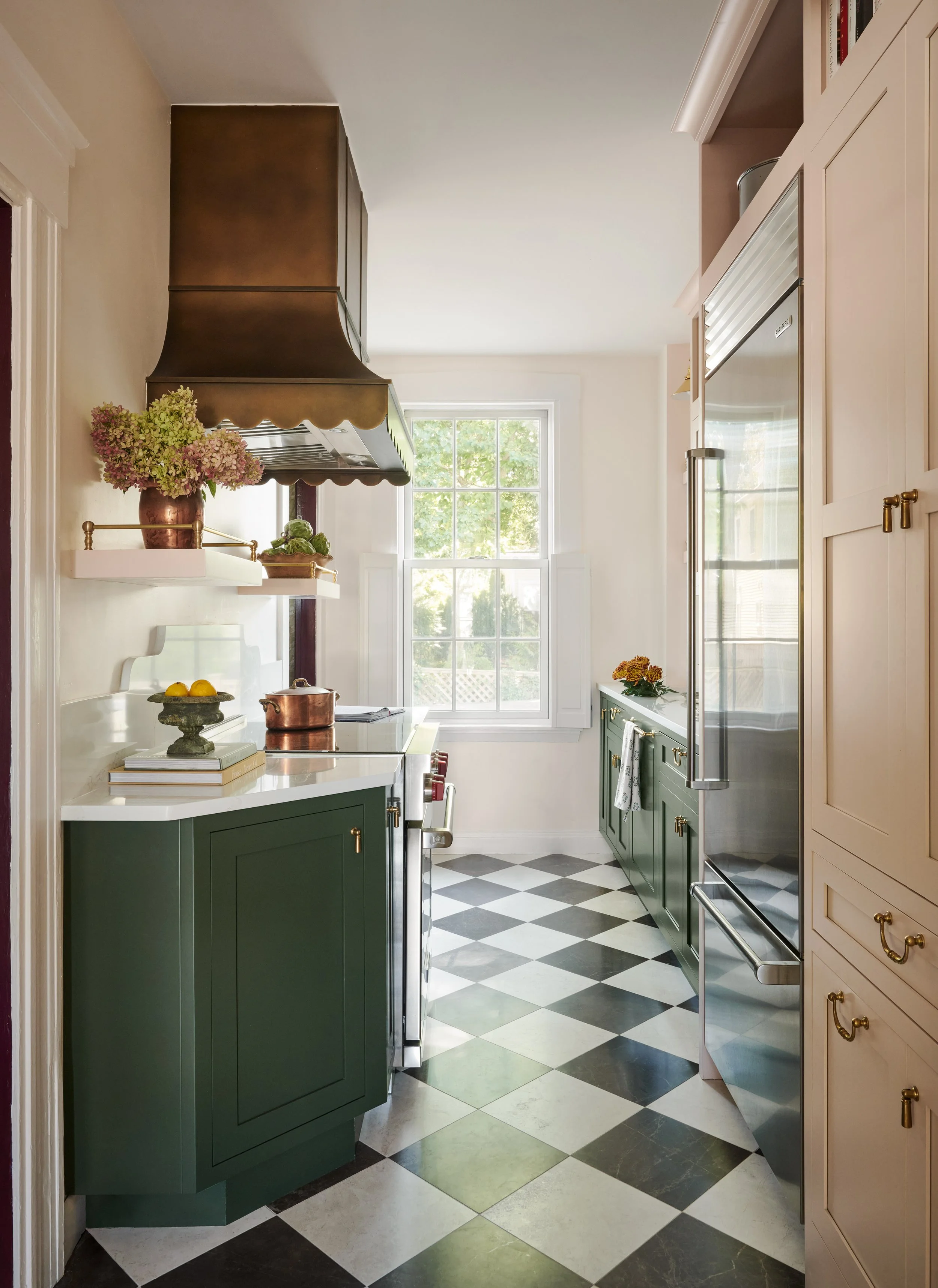Galley kitchen with scalloped brass range hood and black and white checkerboard floor at Summer Street, Newburyport, designed by Ivory & Bone Interiors