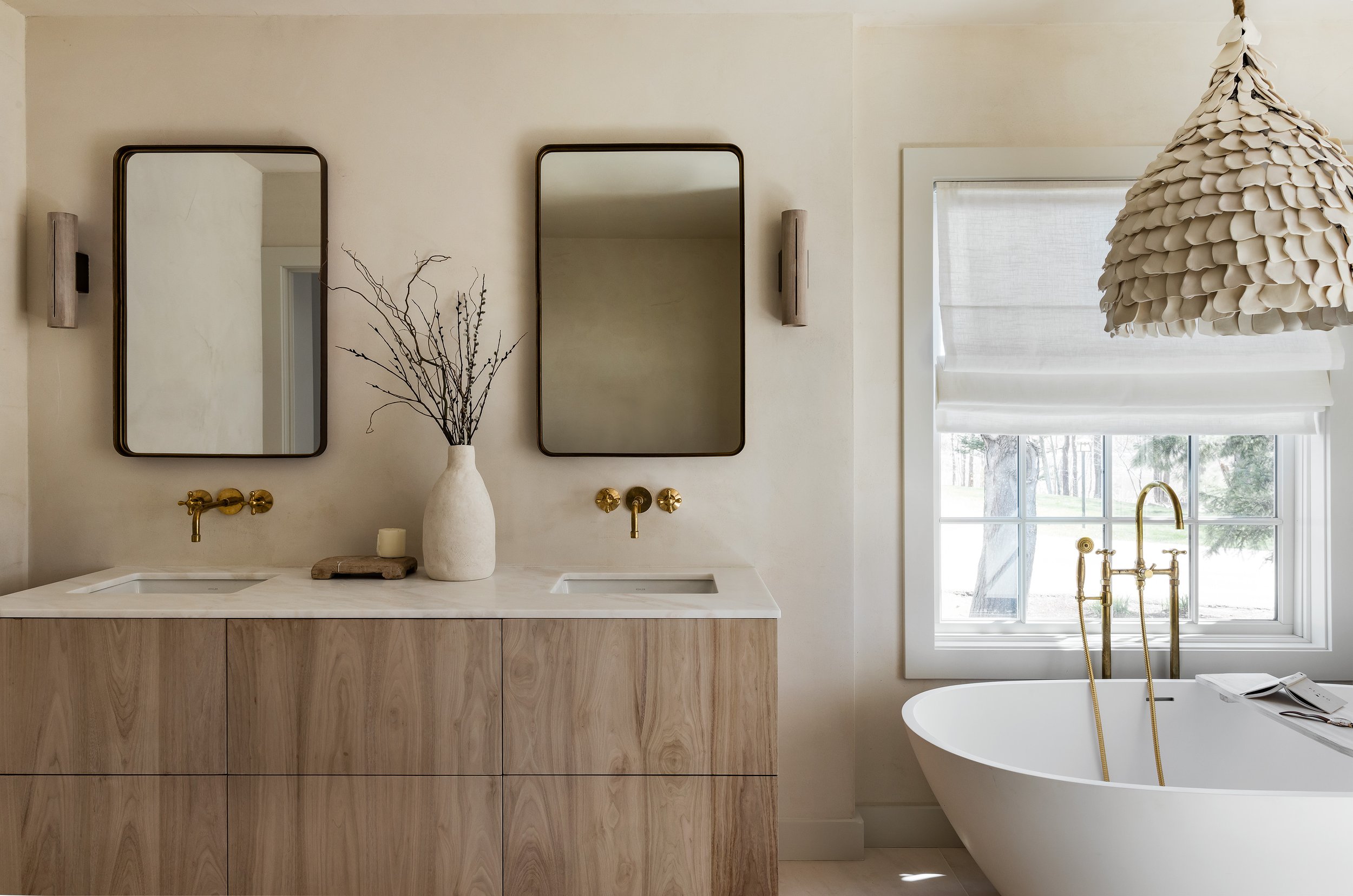 Primary bath with plaster walls, wood double vanity, unlacquered brass fixtures and freestanding tub in a Wild Rose Lane renovation by Ivory & Bone Interiors