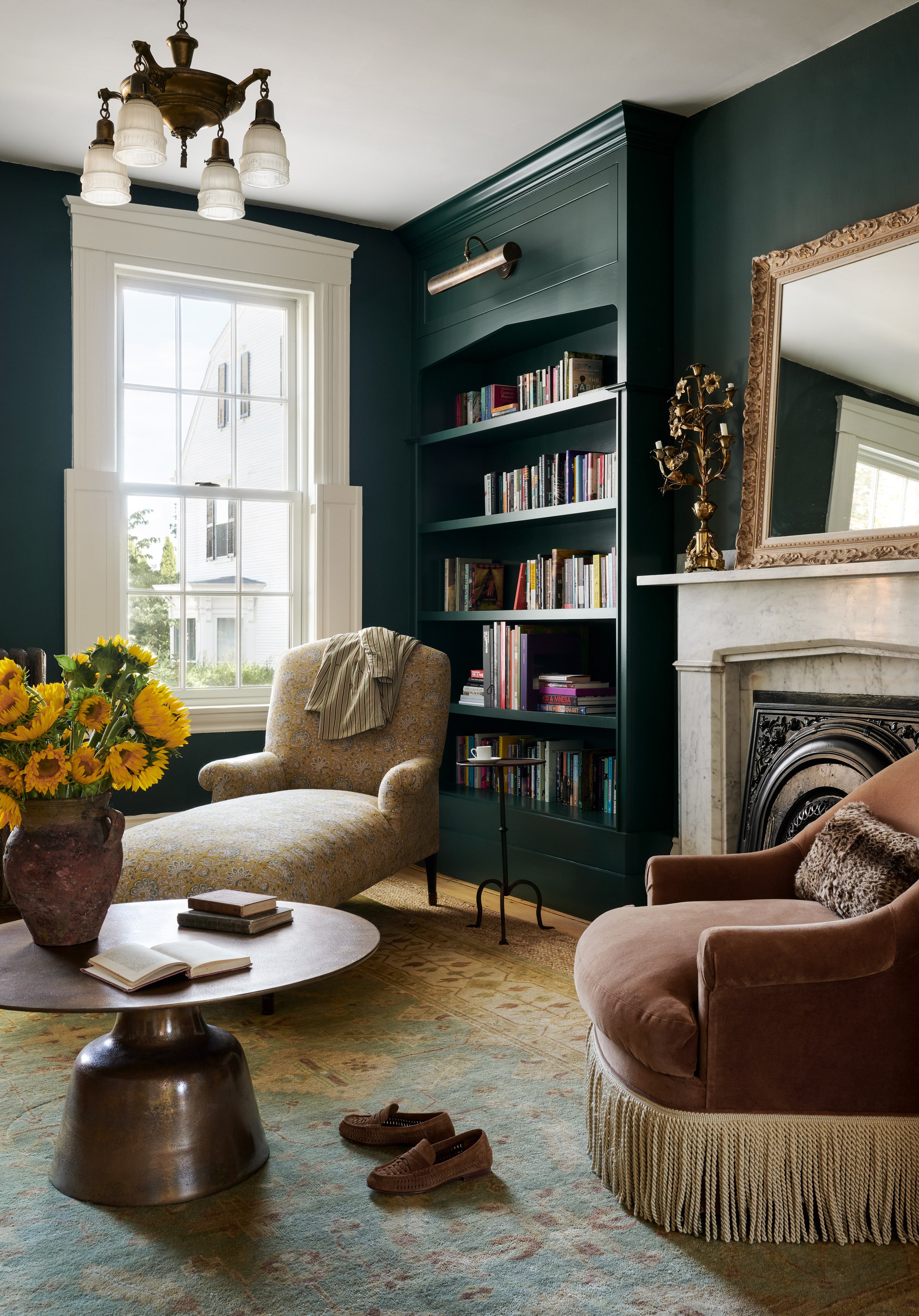 Green library with a patterned chaise, built-in bookshelves and a marble fireplace at Summer Street, Newburyport, designed by Ivory & Bone Interiors