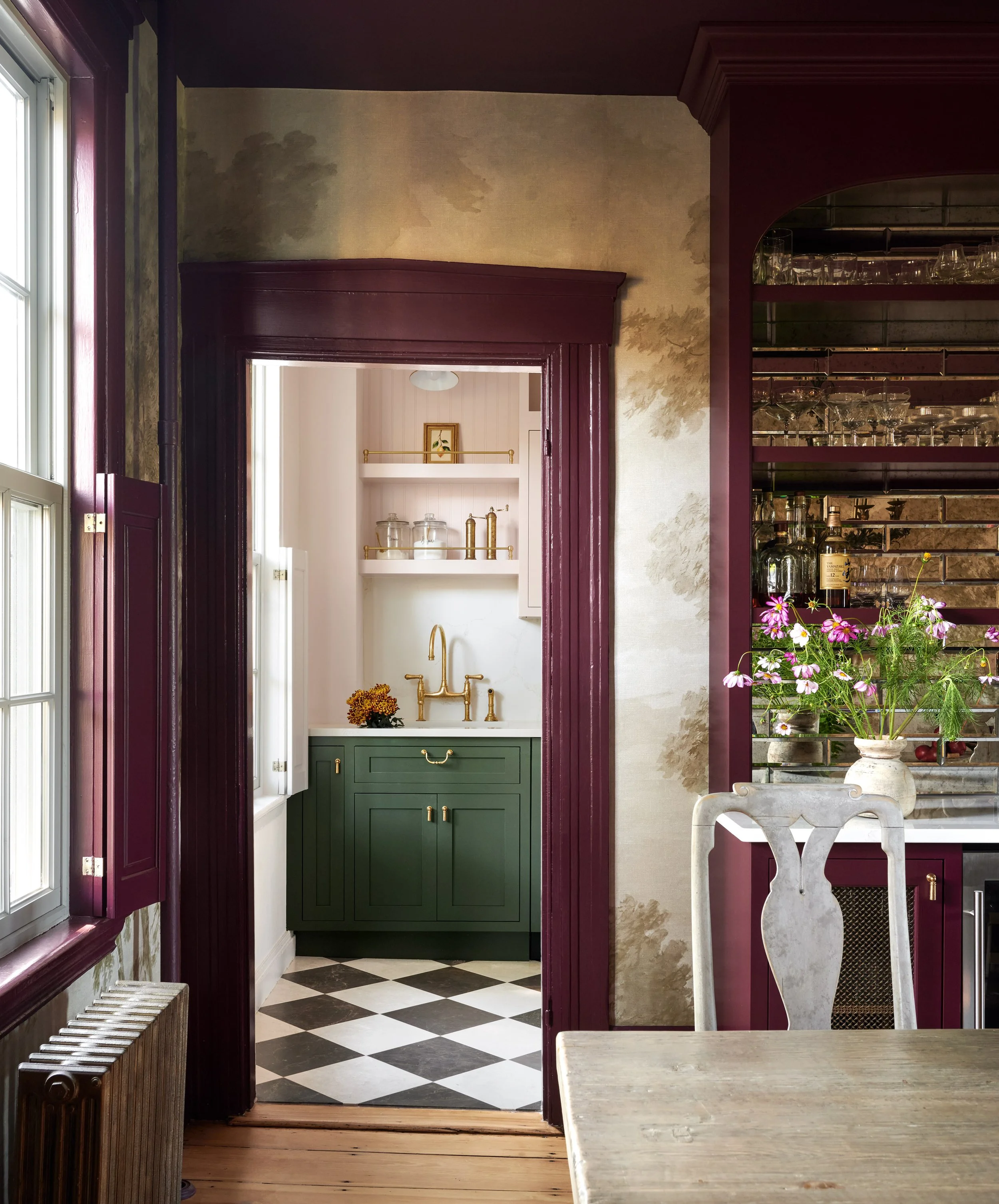 Plum-trimmed doorway to a green and blush kitchen, beside a mirrored bar, at Summer Street, Newburyport, designed by Ivory & Bone Interiors
