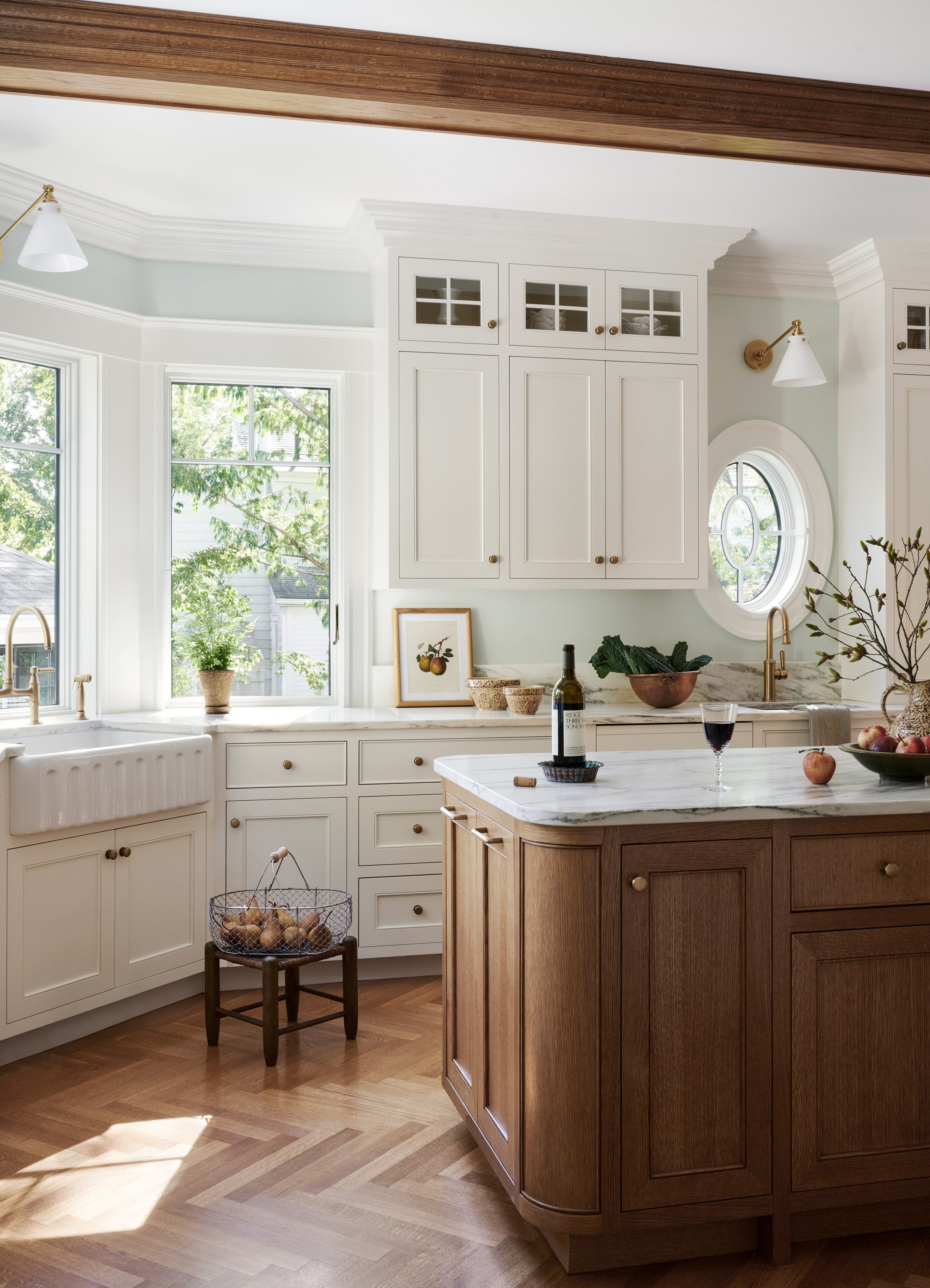Kitchen with oval window and oak island on herringbone floors at Whitmore Road, Newburyport, designed by Ivory & Bone Interiors