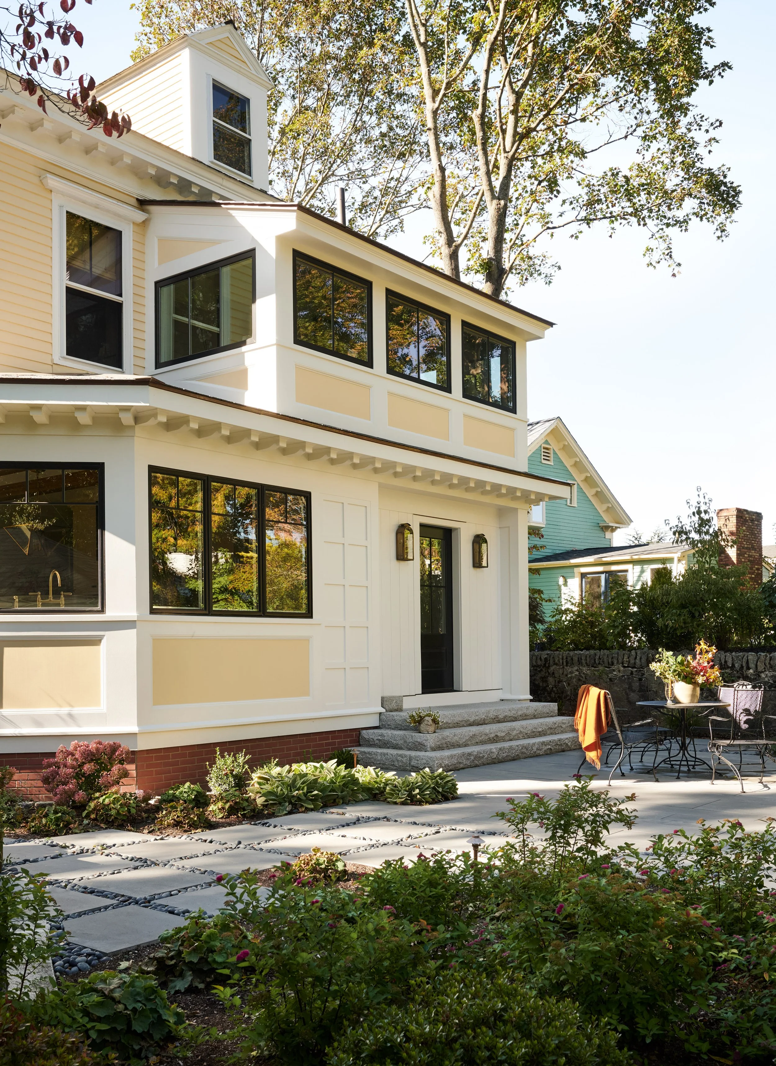 Cream and yellow facade with stone patio and garden at Whitmore Road, Newburyport, designed by Ivory & Bone Interiors